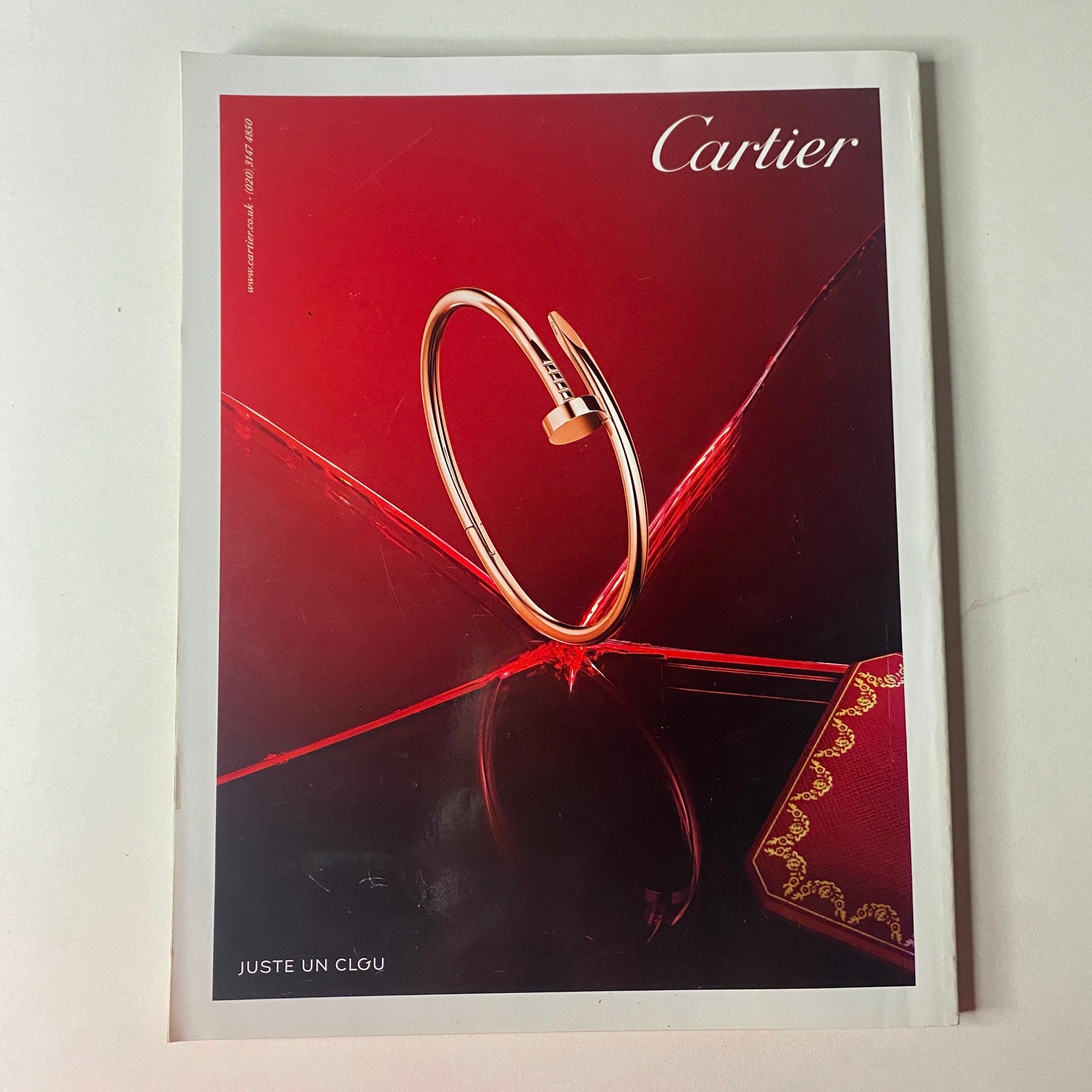 Cover of Cartier magazine featuring a striking 'Juste Un Clou' bracelet against a red backdrop, promoting luxury fashion jewelry.
