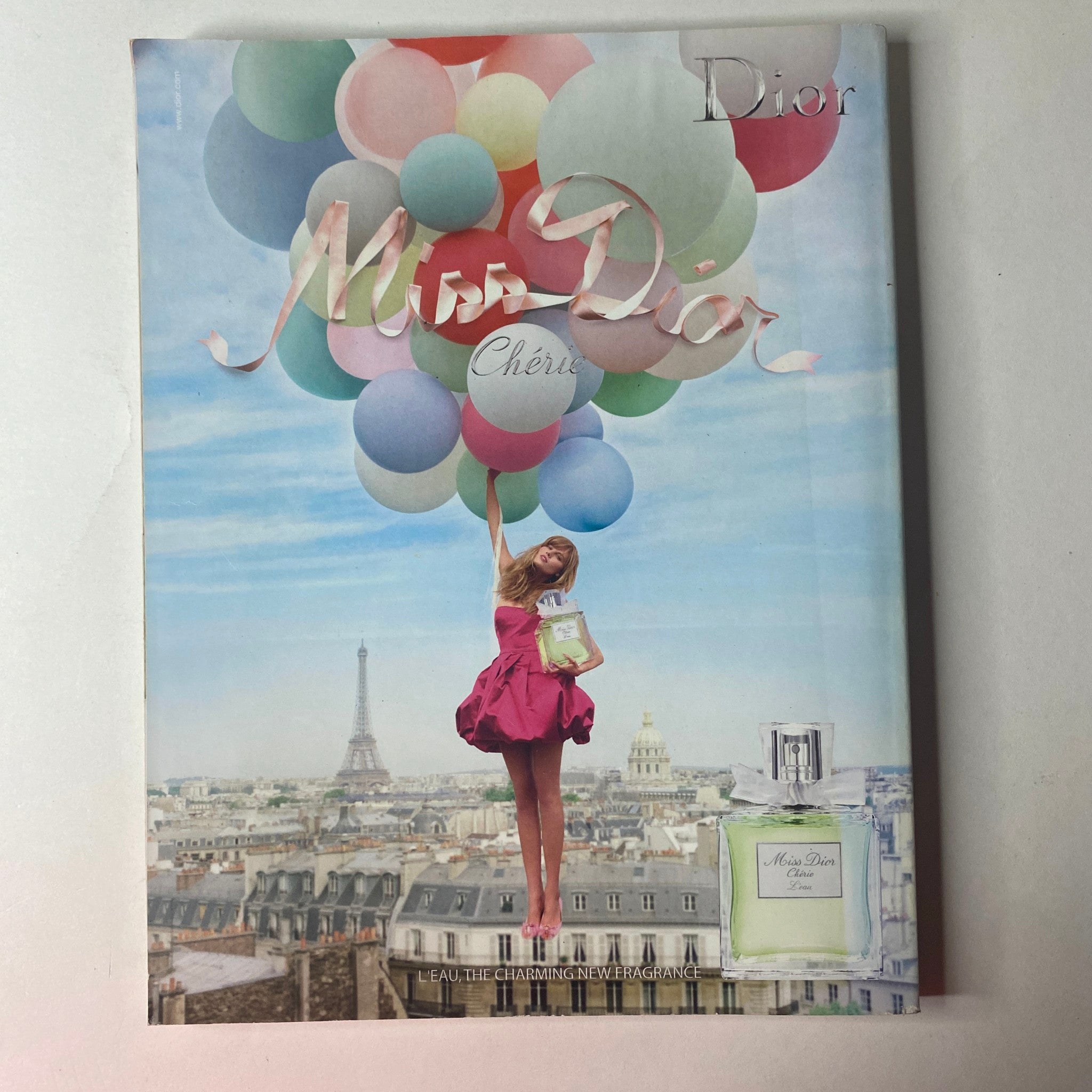Vogue British Magazine June 2009 cover of Miss Dior Cherie with a model holding balloons against a picturesque Paris backdrop, promoting the fragrance.
