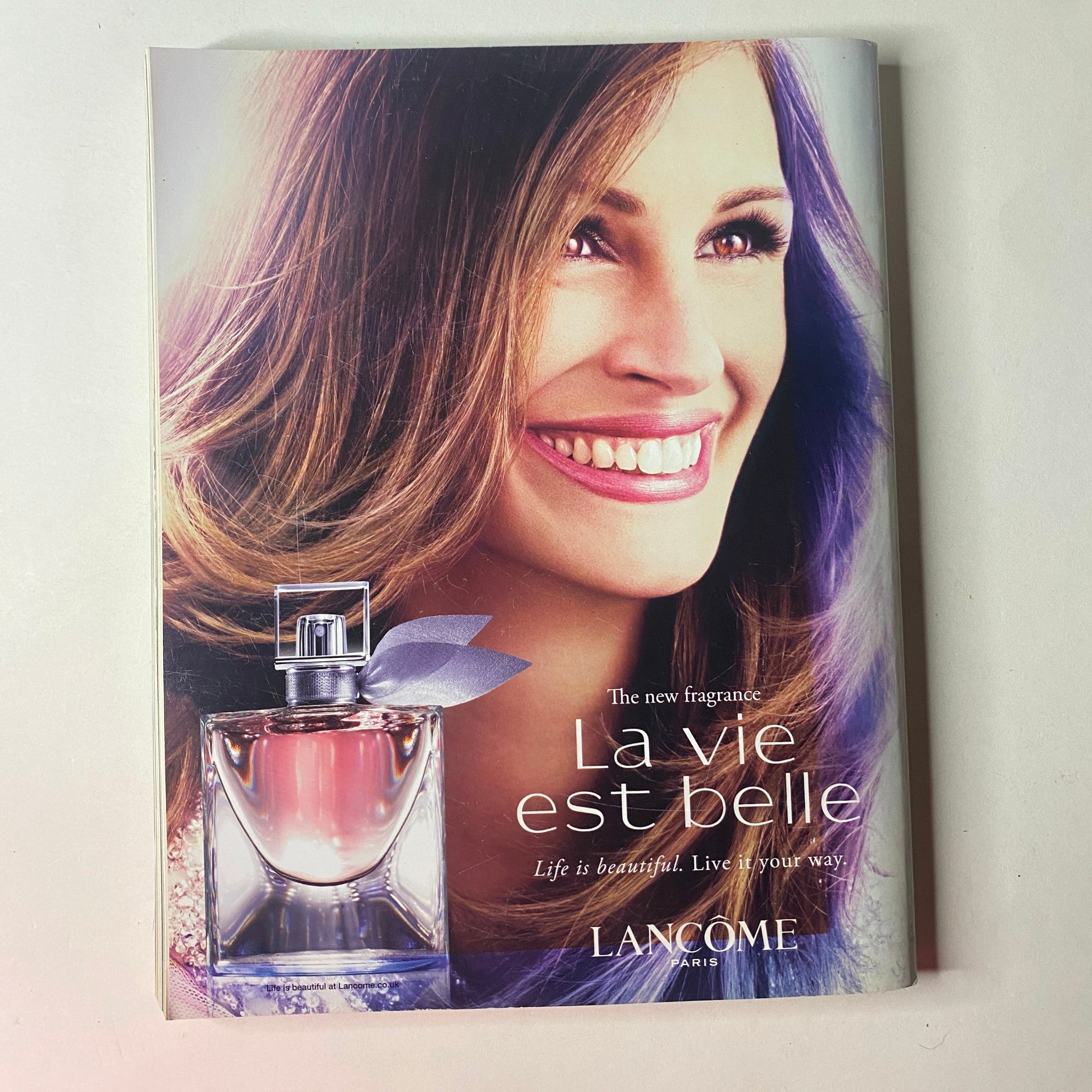 Vogue British Magazine March 2013 Cara Delevingne Cover promoting Lancôme's new fragrance 'La Vie Est Belle' with a smiling model and elegant perfume presentation.