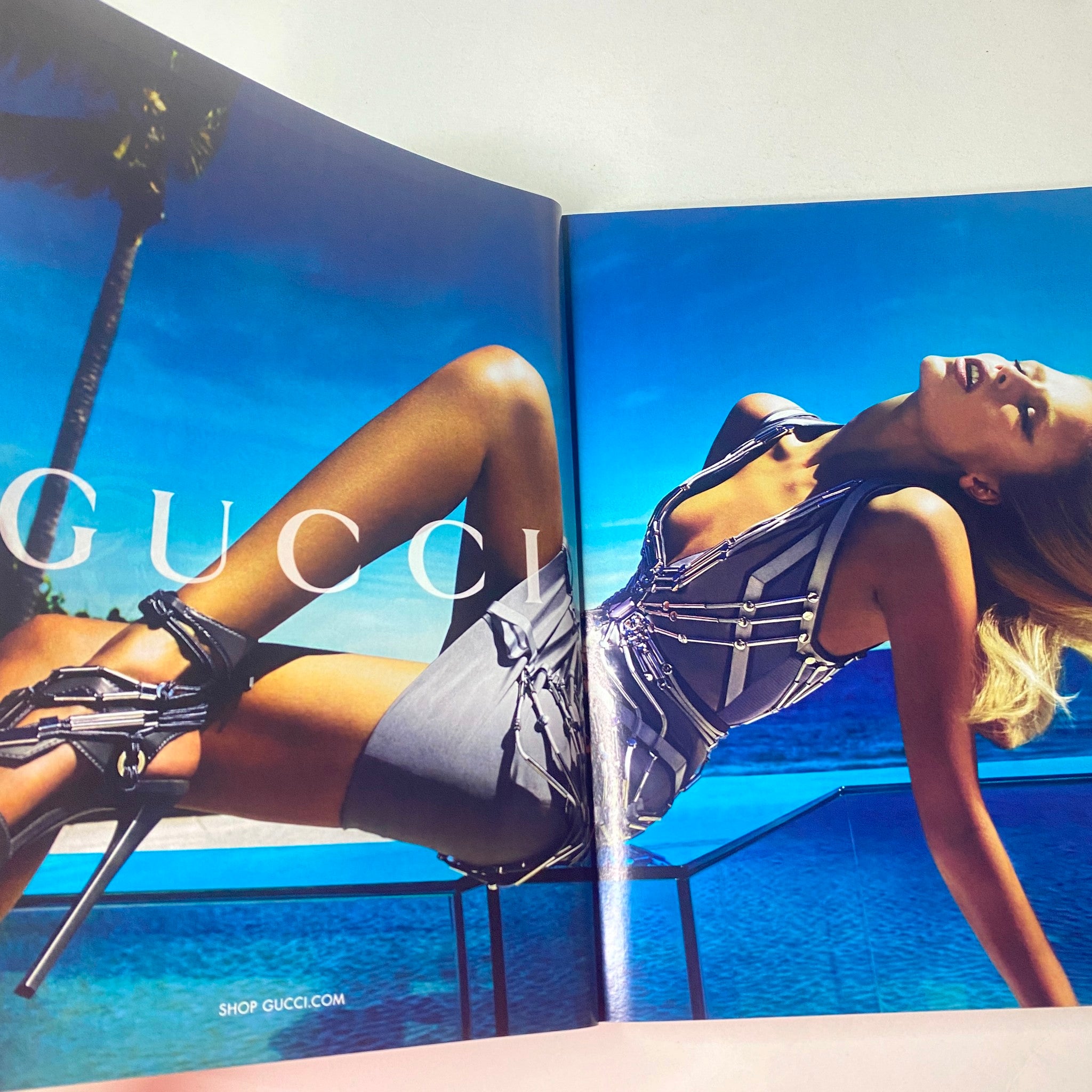 Vogue British Magazine March 2010 displaying a Gucci advertisement featuring a glamorous model in a chic outfit against a vibrant blue background.