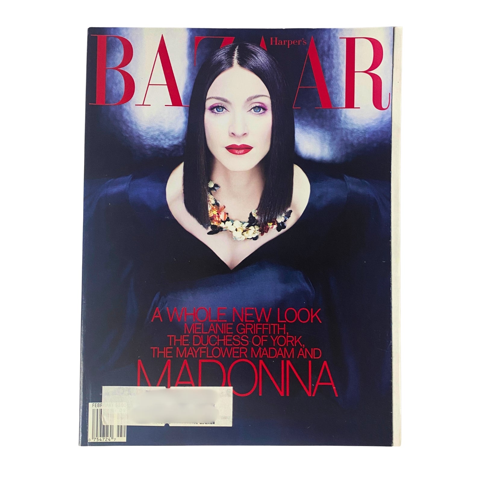 Cover of Harper's Bazaar Magazine February 1999 featuring Madonna. The cover showcases Madonna in a black dress with a vibrant floral necklace, highlighting the issue's theme of a new look in fashion.