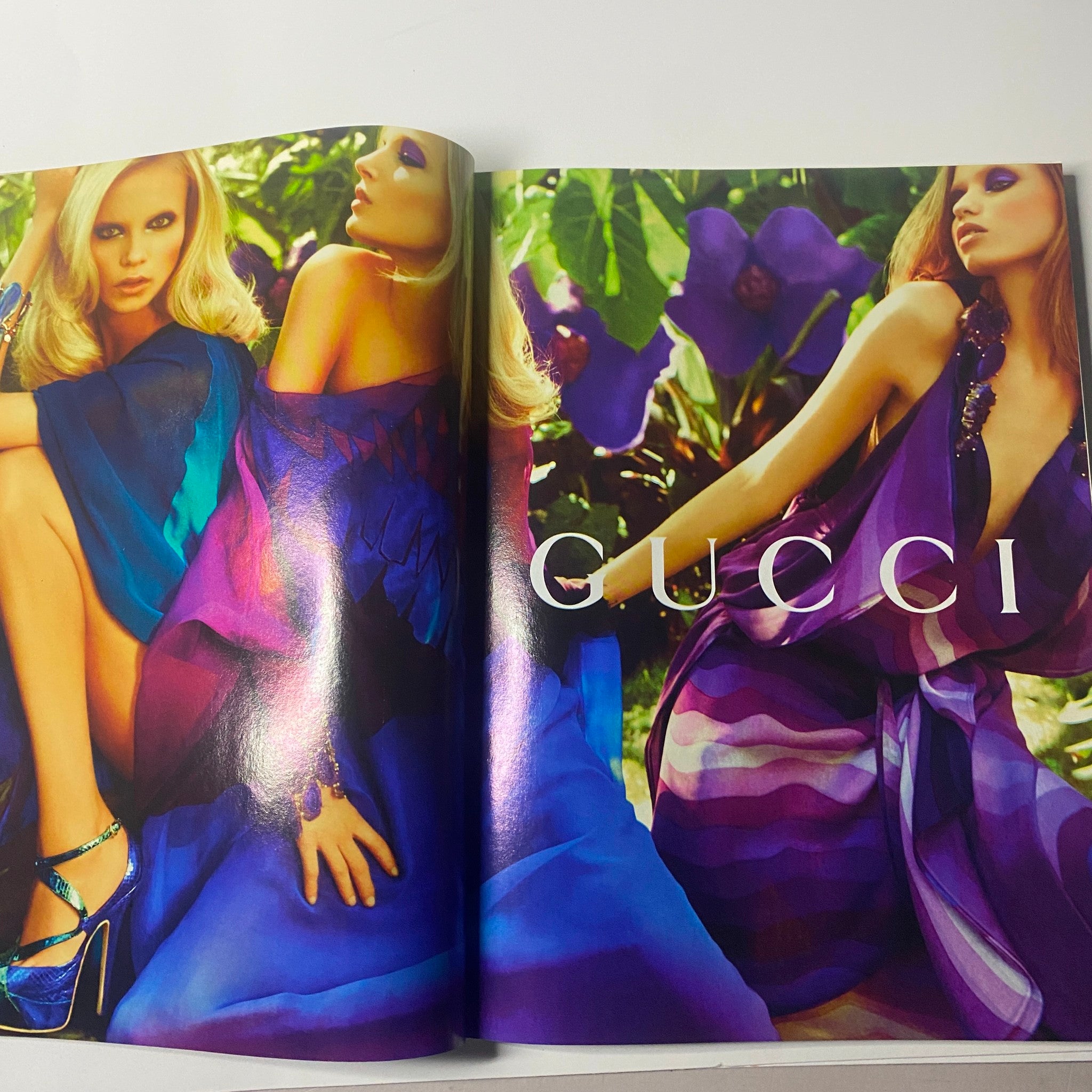 Harper's Bazaar British Magazine April 2009 displays a high-fashion advertisement for Gucci featuring a glamorous model draped in flowing purple and blue gowns against a lush background.