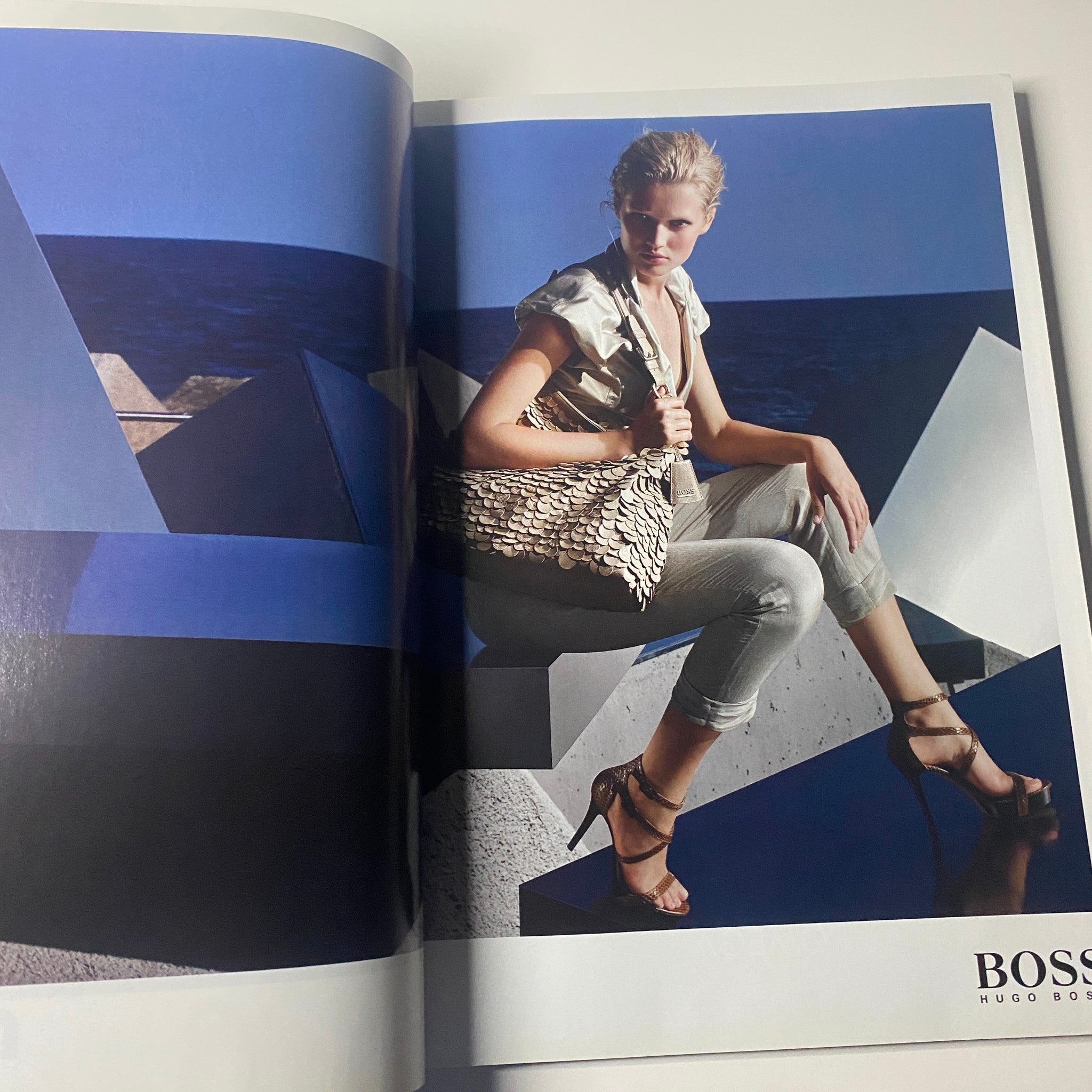 A fashion editorial image from Harper's Bazaar Australia Magazine October 2010 featuring a model in stylish attire sitting against a geometric backdrop, promoting luxury fashion.