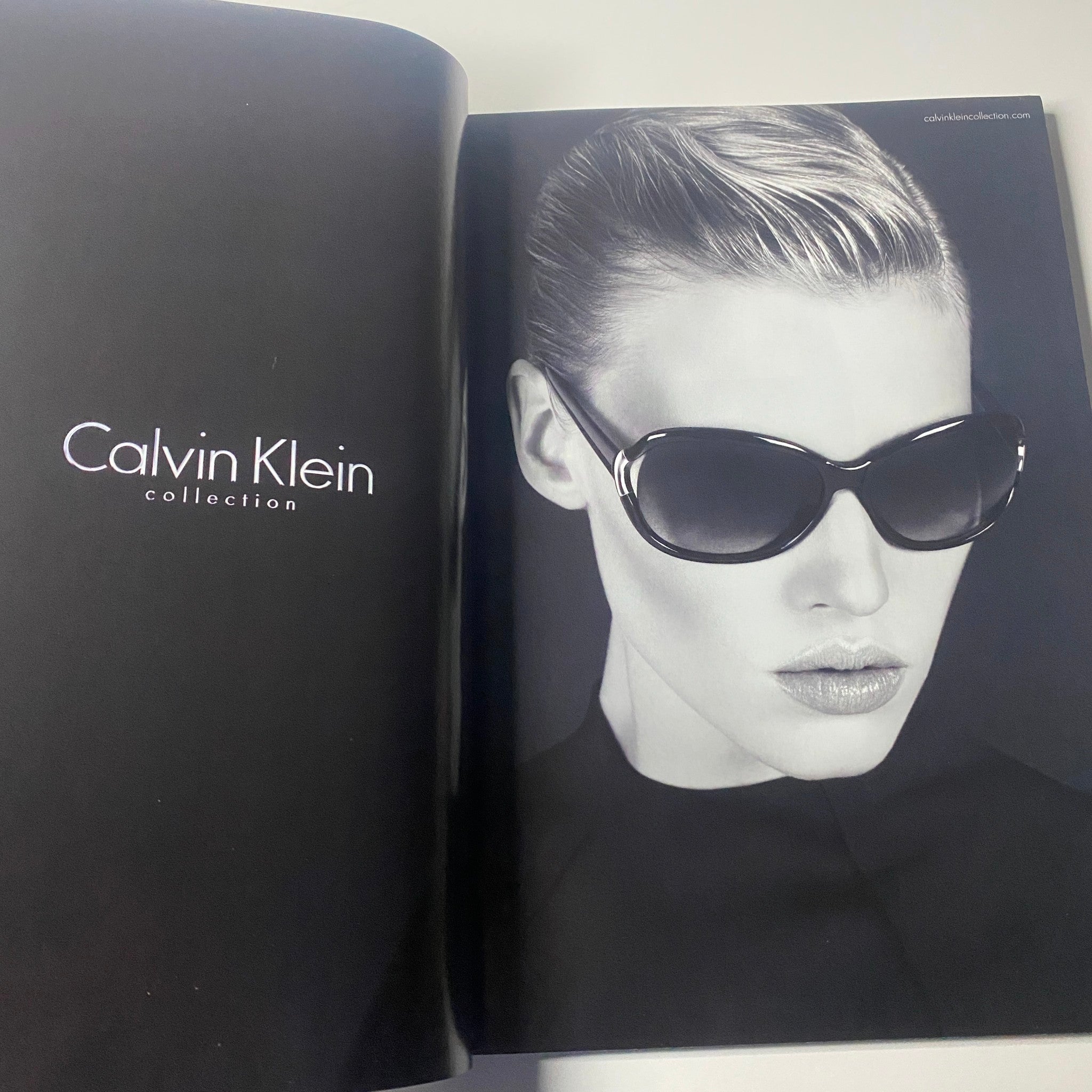A striking black and white fashion image from Harper's Bazaar Australia Magazine October 2010 showcasing a model in Calvin Klein sunglasses, emphasizing modern elegance and chic style.