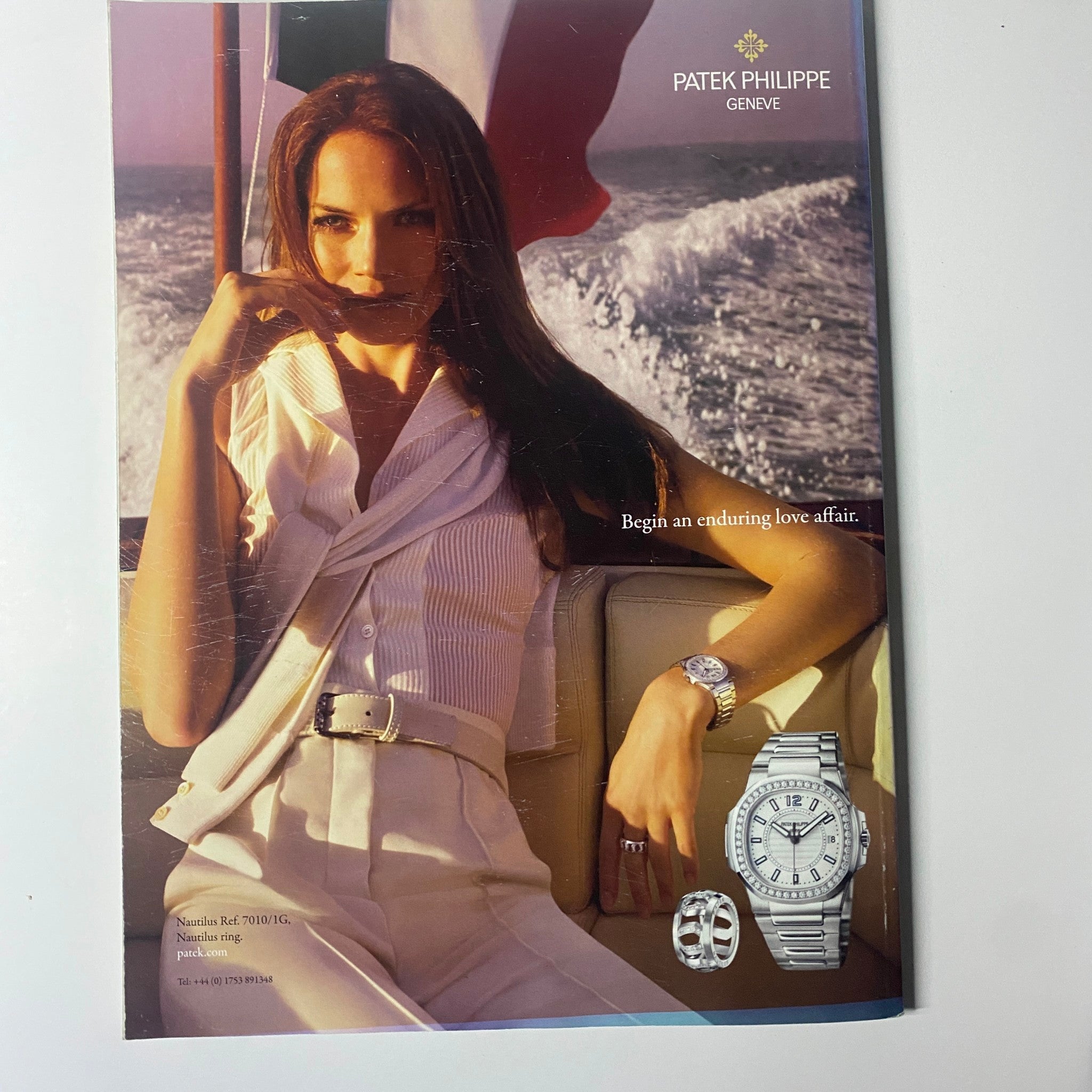 Luxury advertisement for Patek Philippe featuring a woman wearing elegant jewelry and timepiece, promoting the tagline 'Begin an enduring love affair'.