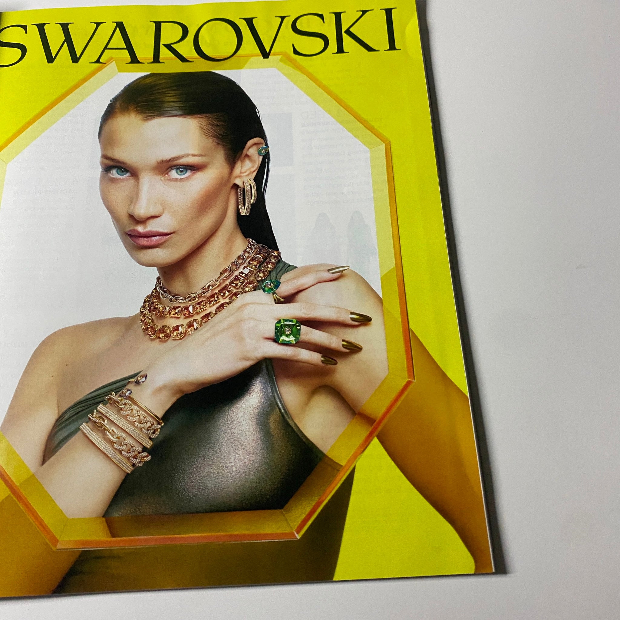 Ad for Swarovski featured in Harper's Bazaar Magazine August 2022, showcasing extravagant jewelry styled on a model with striking features.