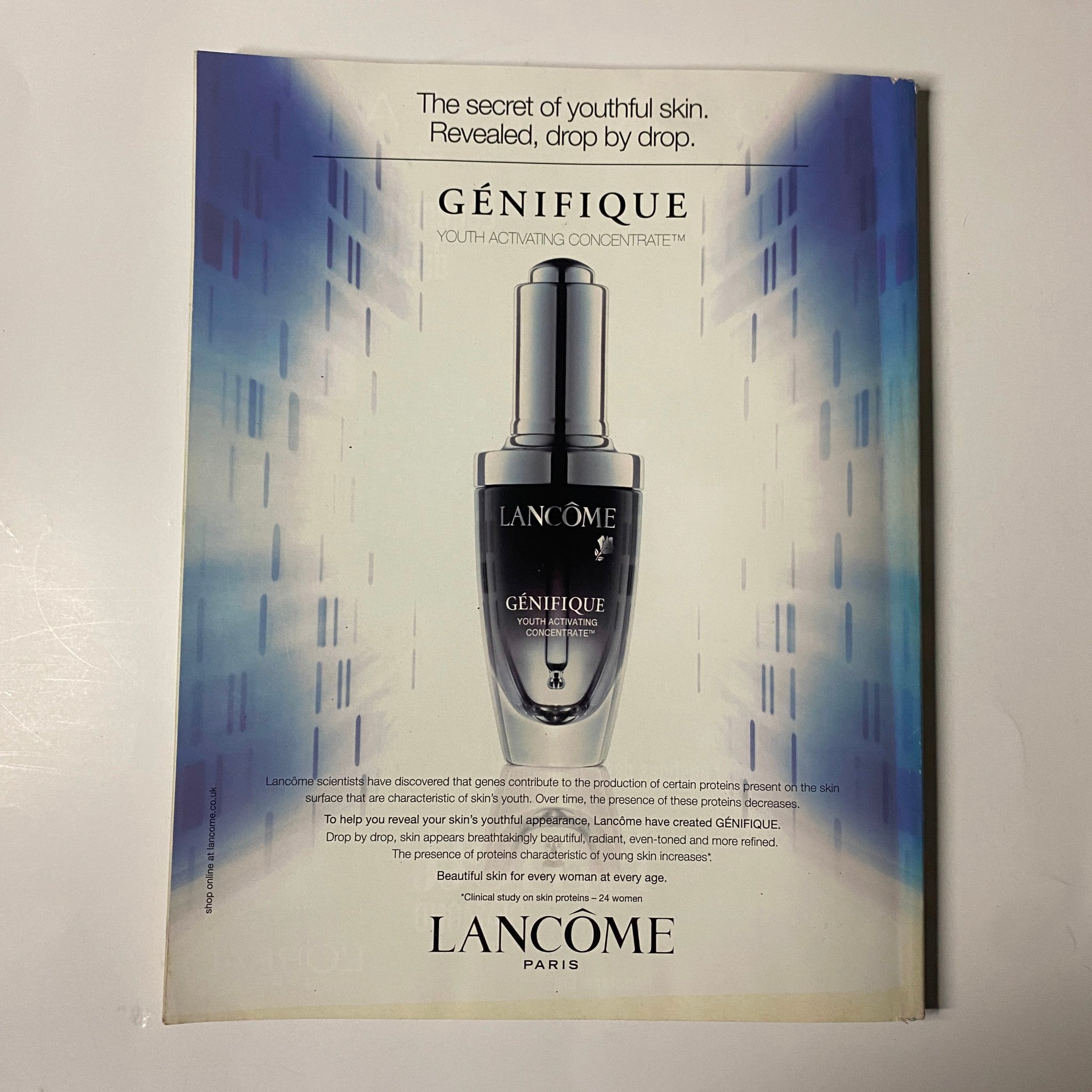 Elle UK Magazine June 2009 Reese Witherspoon Cover: A Lancôme advertisement for Génifique, featuring a sleek serum bottle against a modern, abstract background.