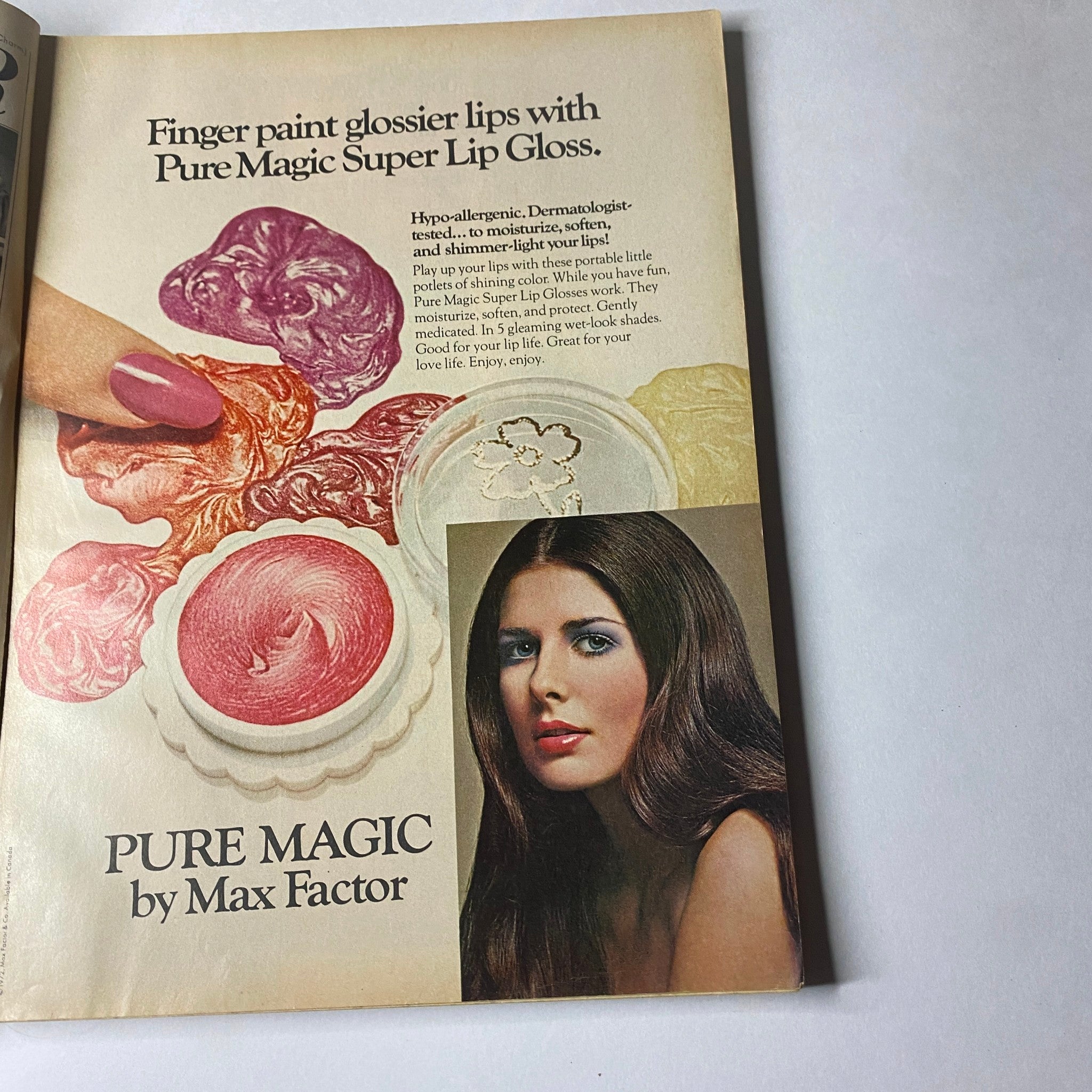Advertisement from Glamour Magazine May 1972 for Pure Magic Super Lip Gloss by Max Factor, displaying colorful lip glosses and a model demonstrating the product.