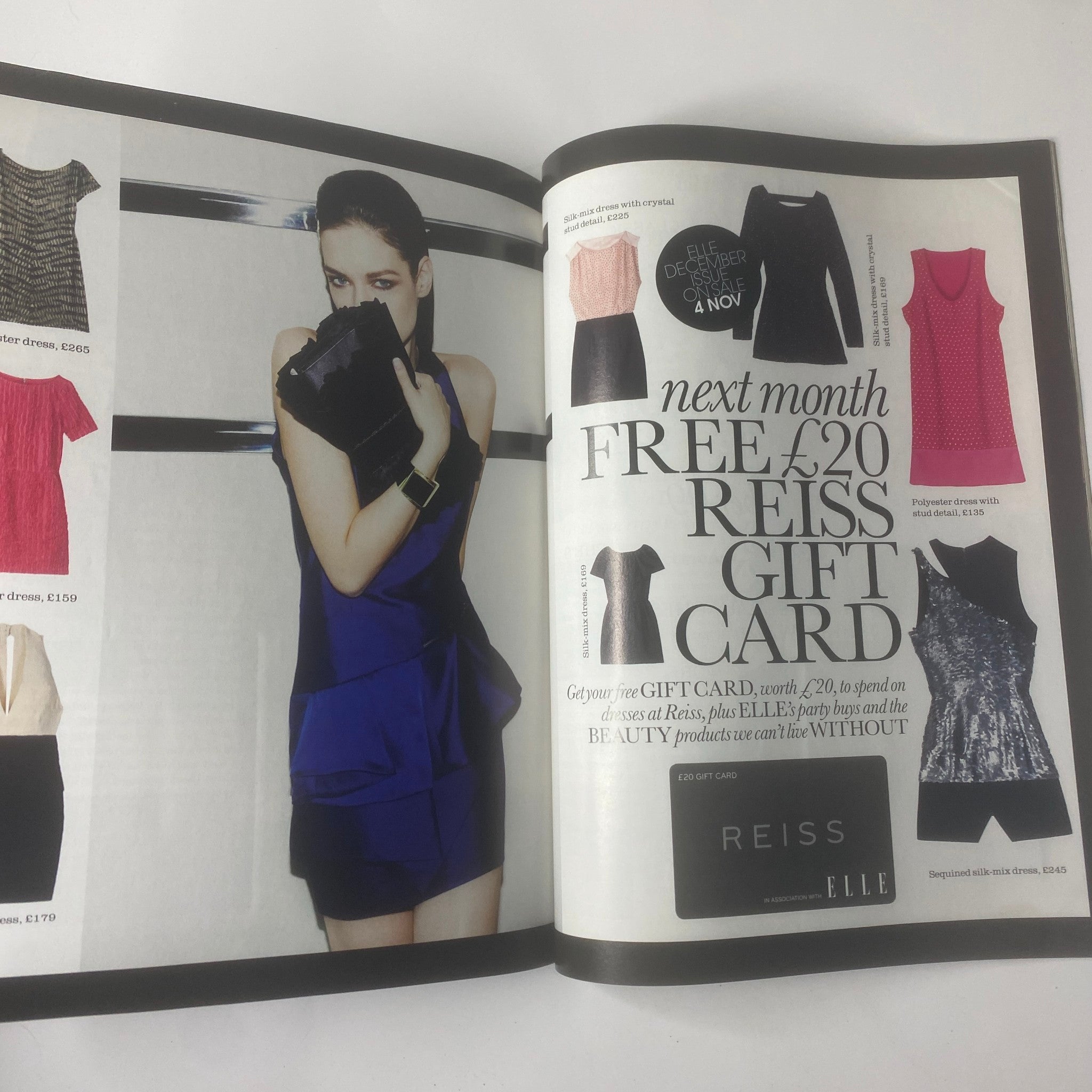Elle UK Magazine November 2009 advertisement for Reiss featuring a model holding a clutch bag with upcoming promotions.