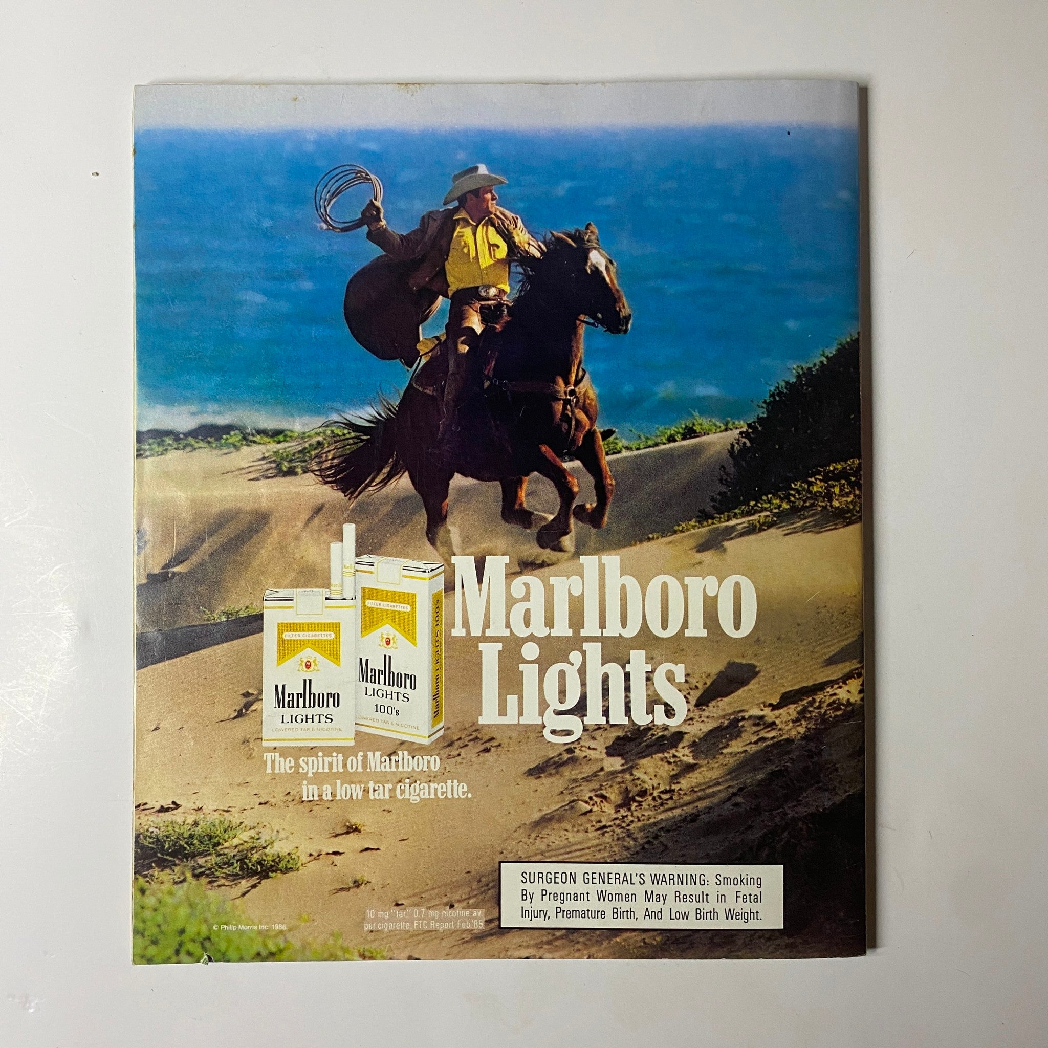 Elle Magazine July 1986 No. 11 Kersti Bowser Cover highlights a vintage Marlboro Lights advertisement depicting a cowboy on horseback by the beach.