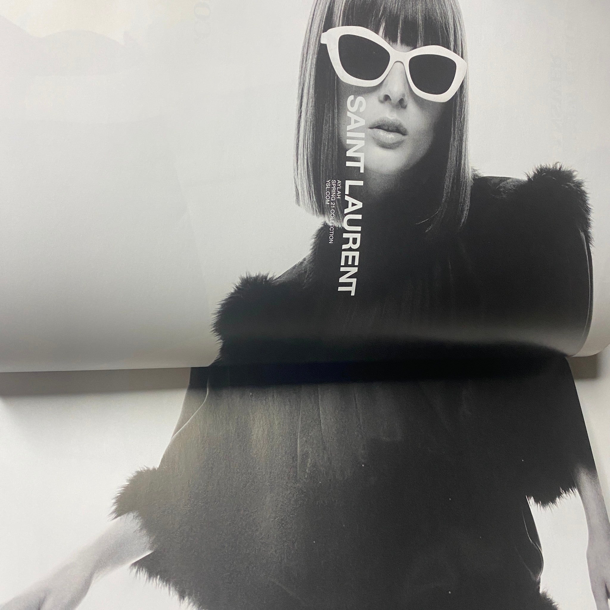 Fashion editorial from W Magazine 2021 Volume 1 highlighting a model in a stylish black outfit with white sunglasses, showcasing Saint Laurent.