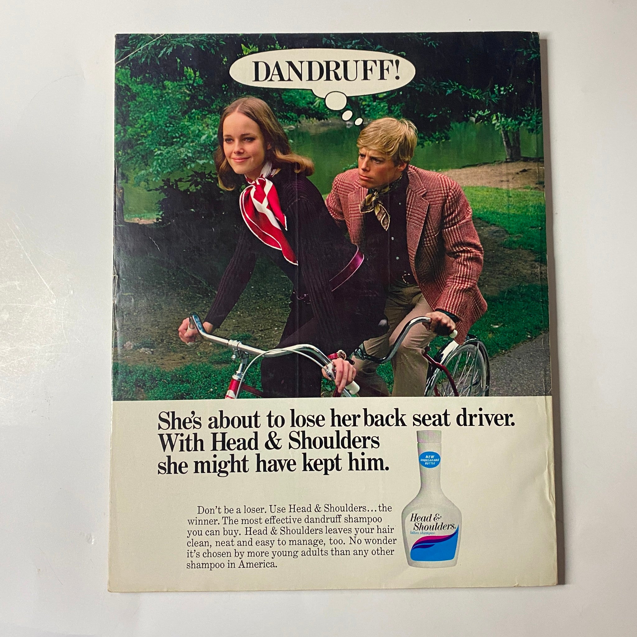Humorous advertisement from Seventeen Magazine November 1969 promoting Head & Shoulders shampoo with a girl and a boy on bicycles.