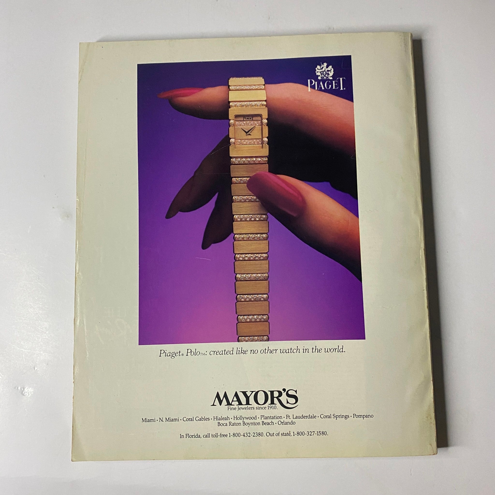 A promotional image featuring a Piaget watch displayed elegantly with a hand adorned in manicured nails. The background is a vibrant purple, enhancing the luxurious appeal of the timepiece. This complements the title 'Town & Country Magazine November 1986 Karen Carter Fortson Cover No Label VG', reflecting the elegance and sophistication associated with both the magazine's themes and Piaget's craftsmanship.