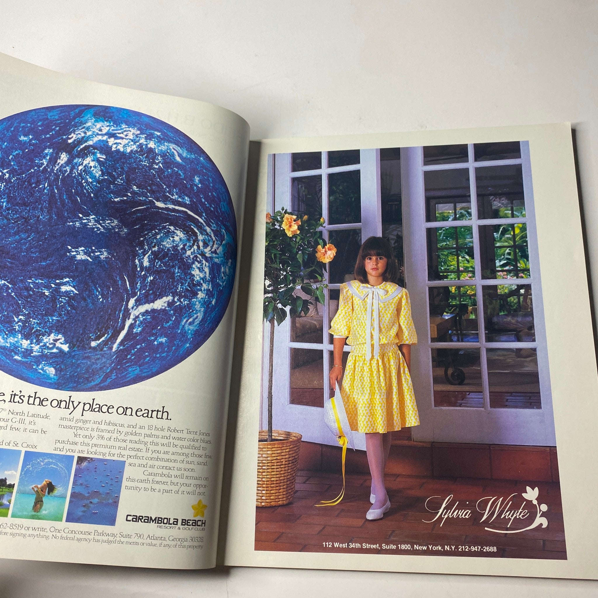 Town & Country Magazine January 1987 Alix Goldsmith Cover No Label VG - A charming advertisement featuring a young girl in a bright yellow dress, promoting Sylvia Myle boutique amidst scenic background visuals.