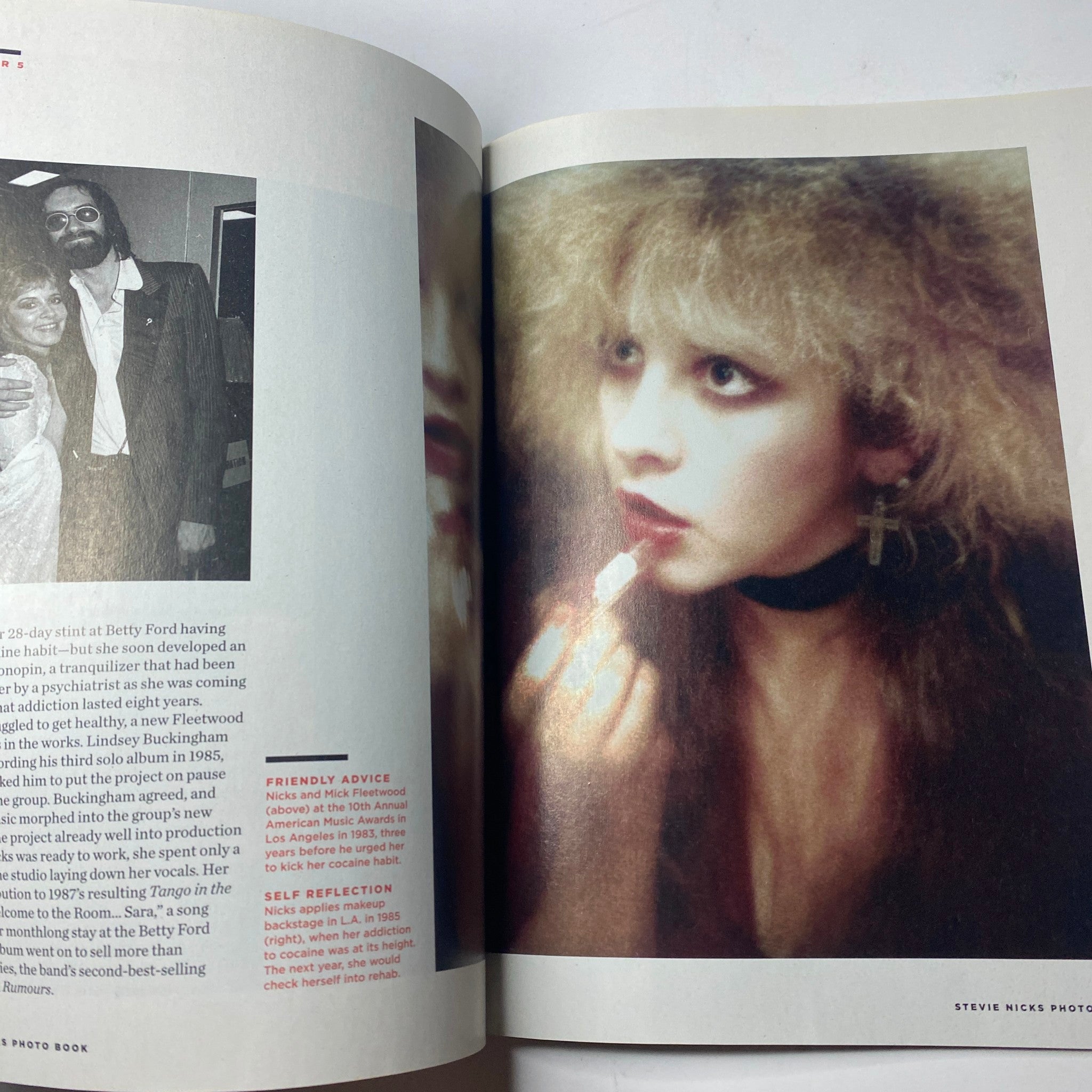 Inside page of 'Stevie Nicks Photo Book' capturing Stevie Nicks applying makeup with a reflective expression, highlighting her personal journey and struggles, set during her time at the Betty Ford Center.