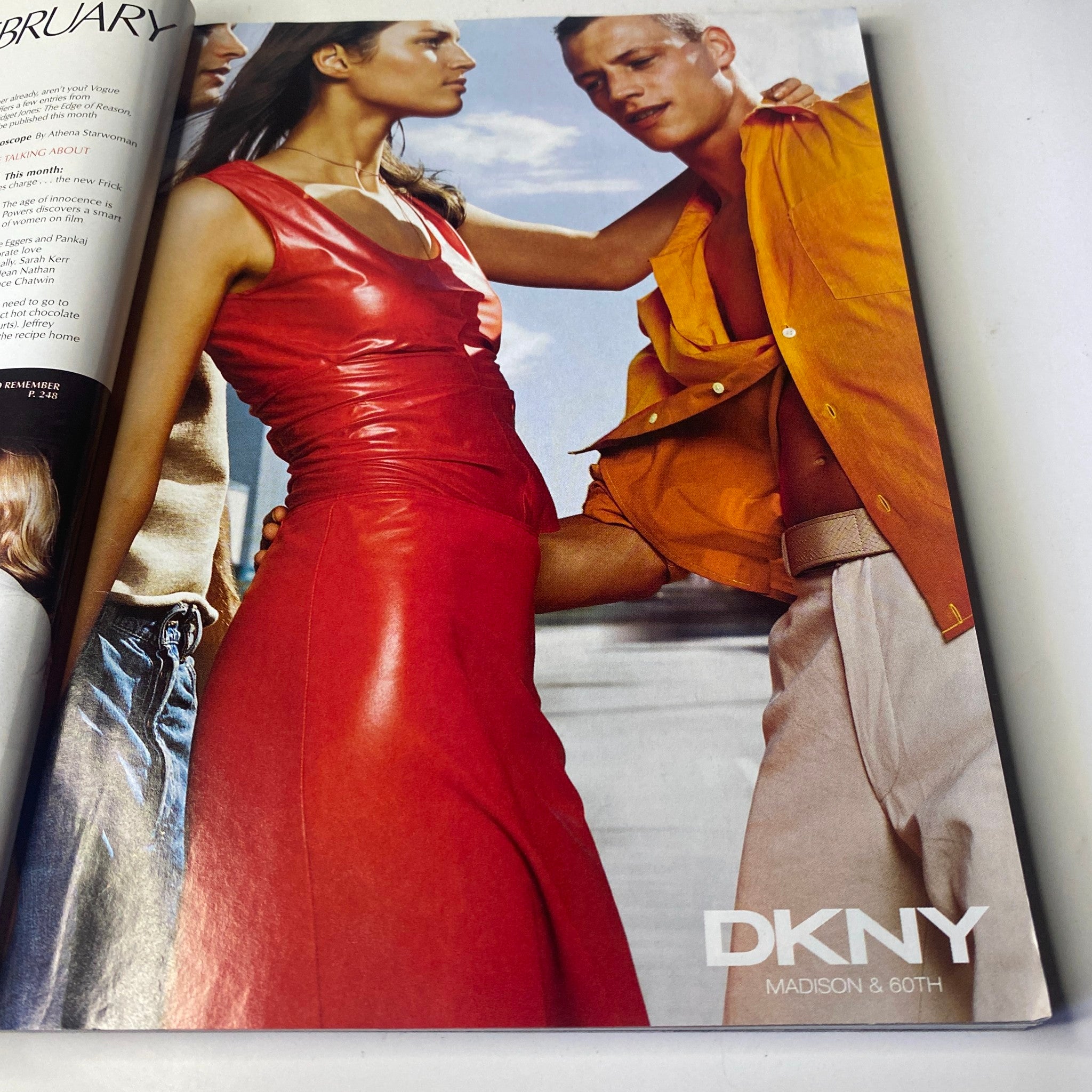 Vogue Magazine February 2000 Angela Lindvall Cover features a DKNY advertisement showcasing a model in a vibrant red dress alongside a male model in an orange shirt, highlighting contemporary fashion trends.