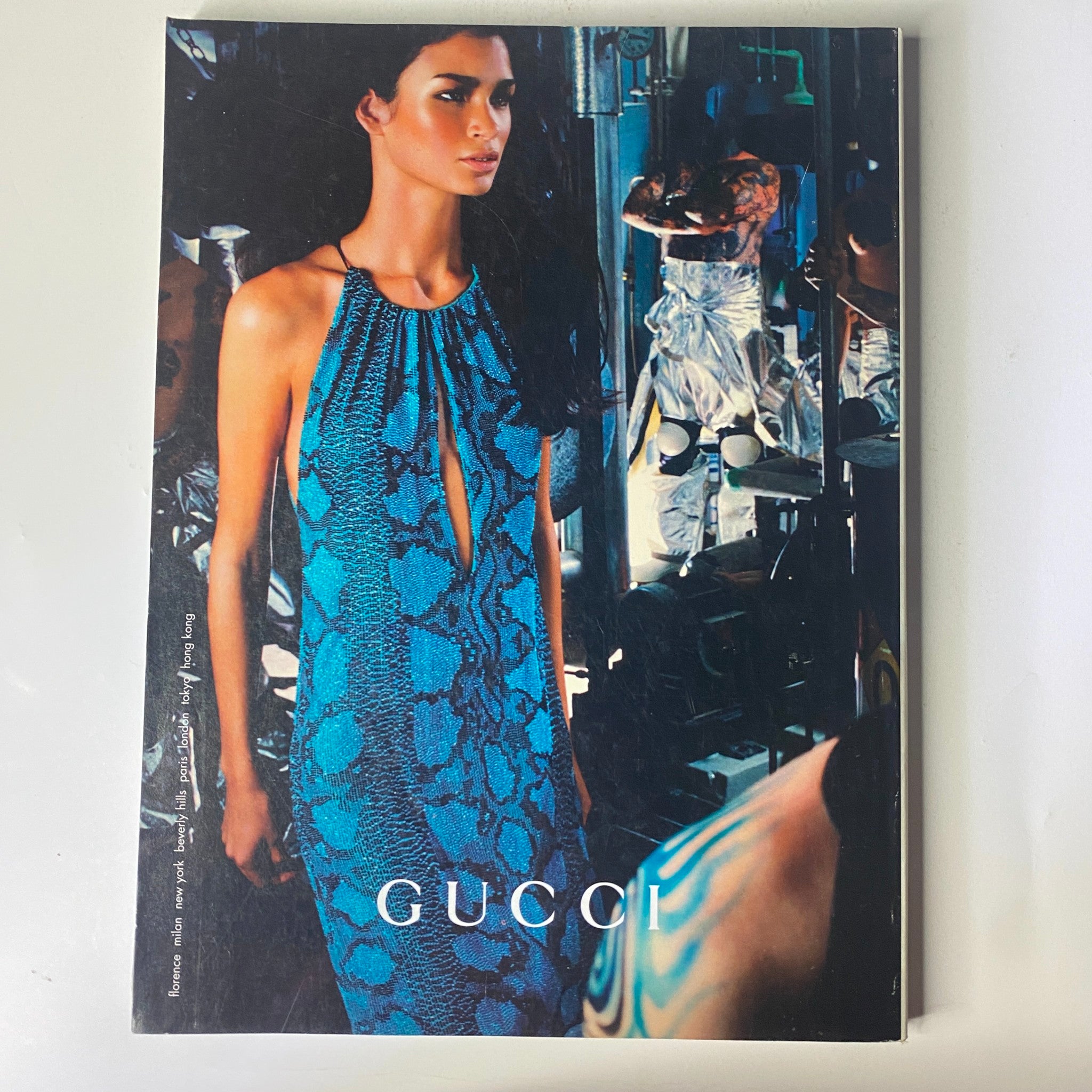 Vogue Magazine February 2000 Angela Lindvall Cover features a Gucci advertisement with a model in a striking blue snake-print dress, set against a dramatic backdrop, illustrating high fashion aesthetics.
