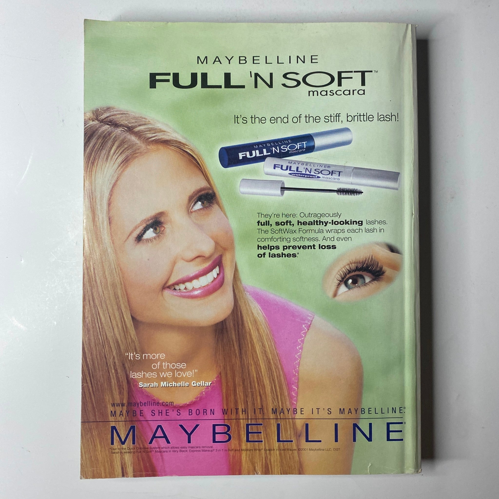 Cover of Maybelline Full 'N Soft Mascara advertisement featuring a smiling woman showcasing thick, healthy-looking lashes. Promoting the benefit of enhancing lashes without stiffness, with the tagline 'It's the end of the stiff, brittle lash!' This is an original advertisement showcasing beauty products.