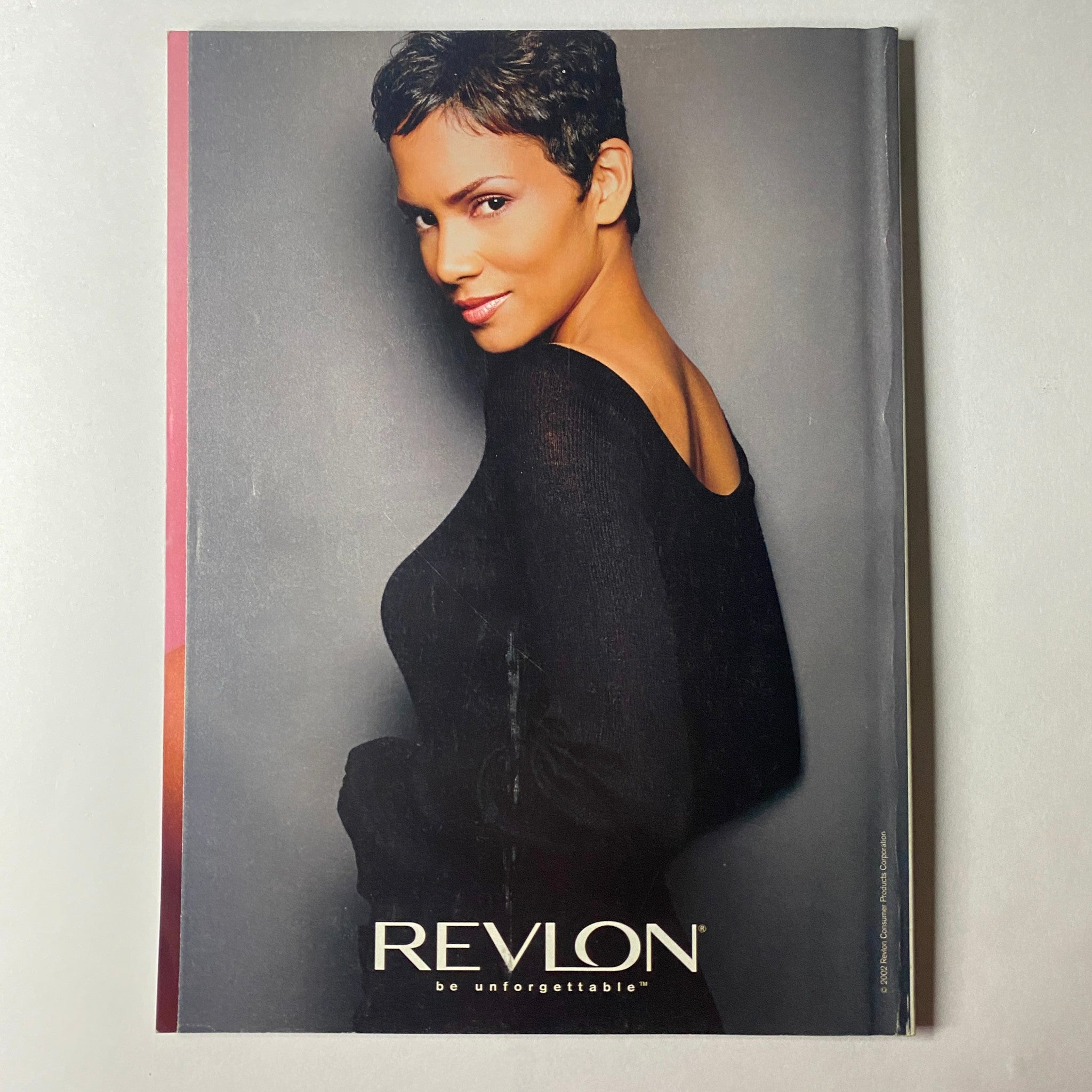 Cover of Vogue Magazine July 2002, featuring Amber Valletta, highlighting fashion with a Revlon advertisement saying 'be unforgettable'.