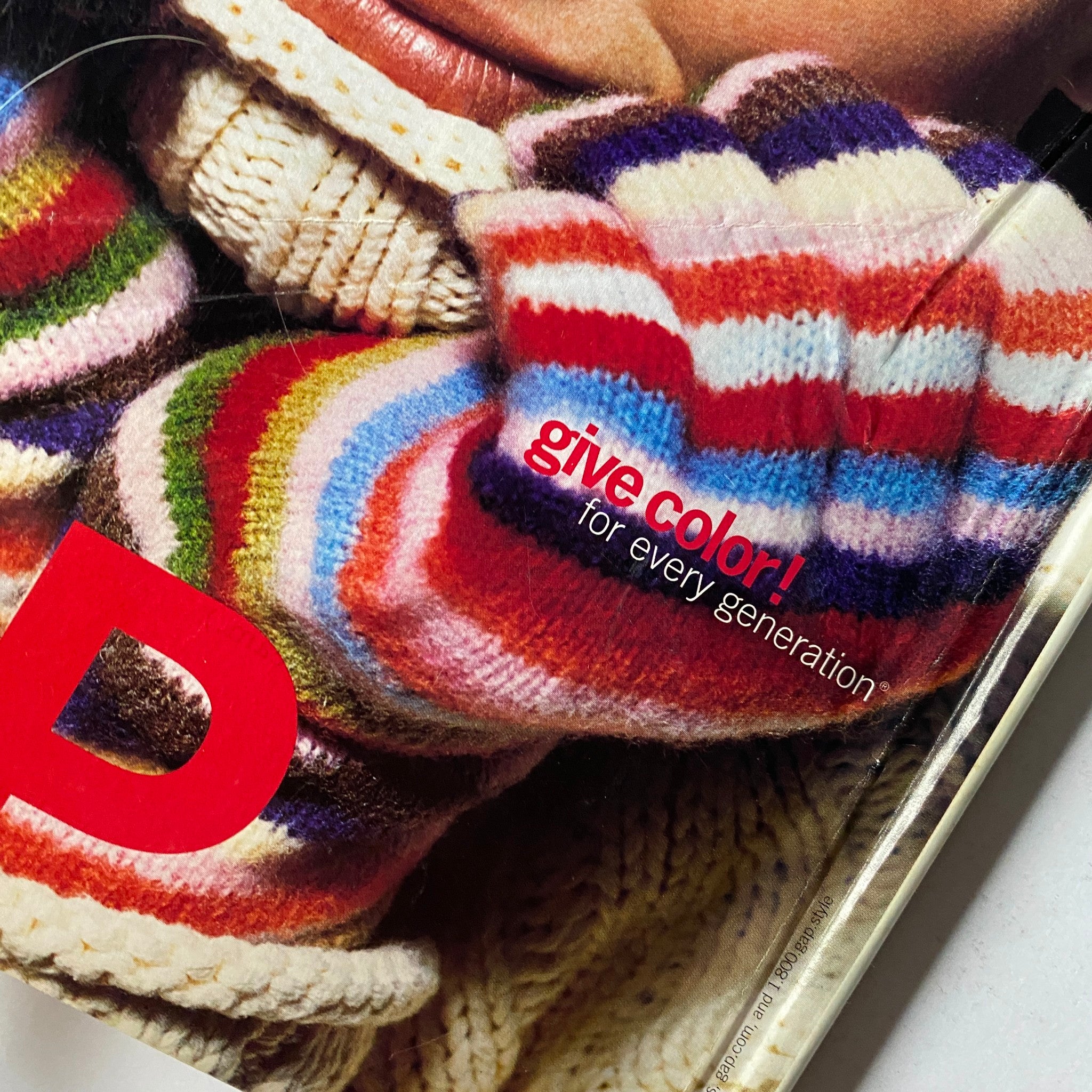 Vogue Magazine December 2002 Halle Berry Cover No Label - Close-up of a GAP advertisement displaying details of colorful striped mittens and a winter sweater.