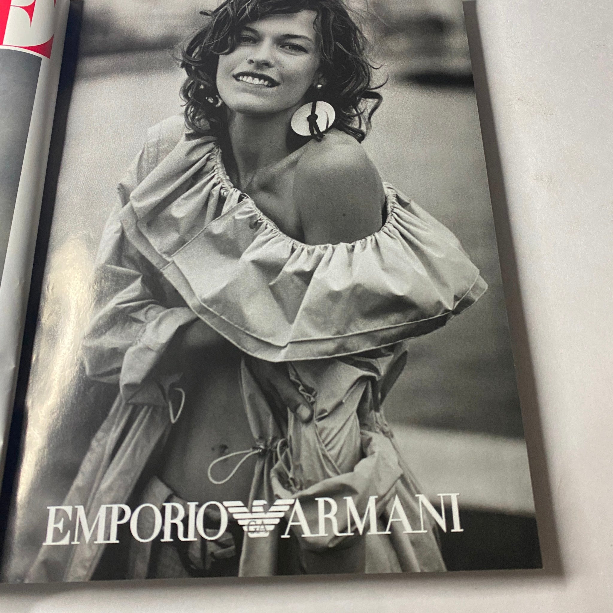 Black and white ad from Vogue Magazine April 2003 showcasing Emporio Armani's fashion collection, focusing on a model wearing an off-shoulder dress.