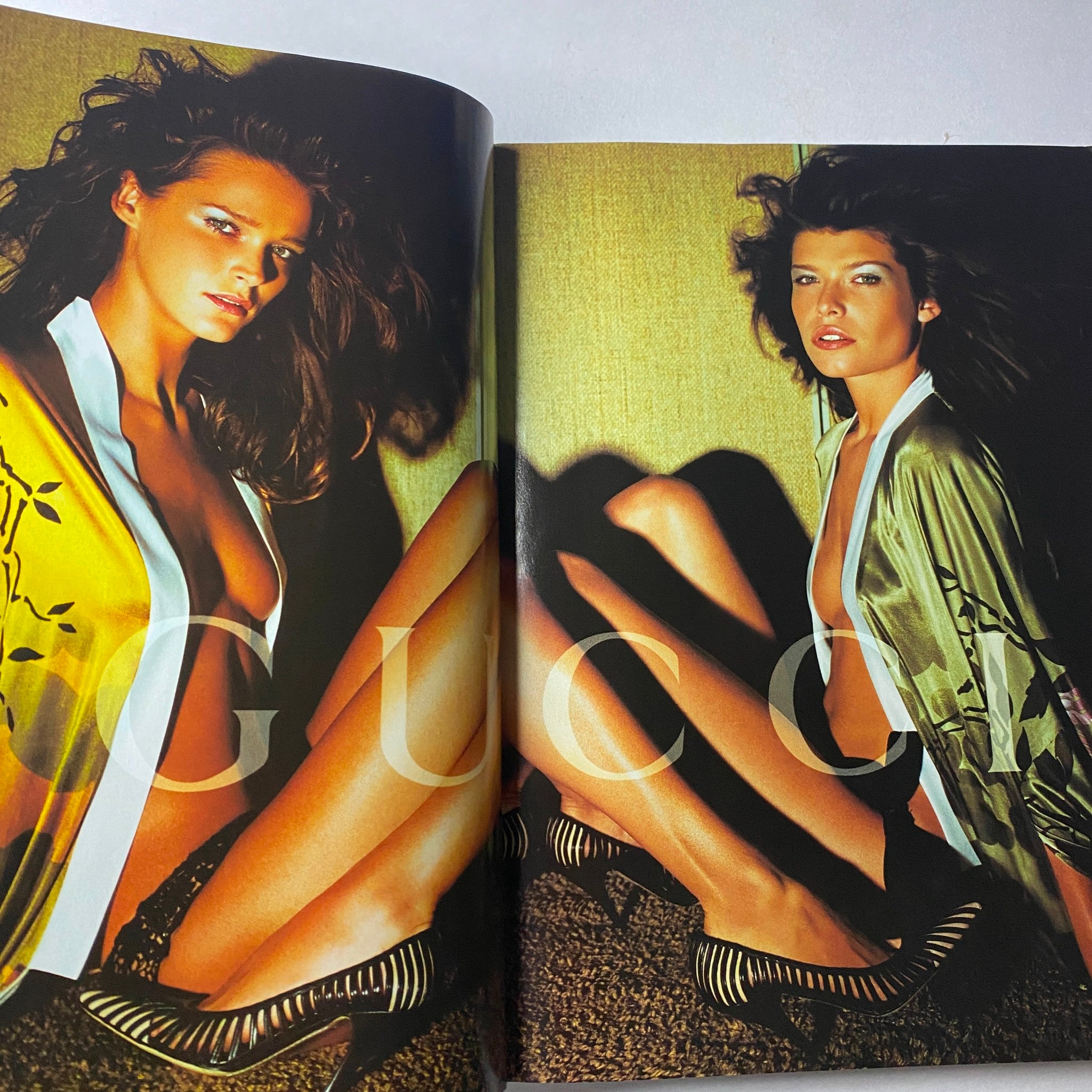 Gucci fashion spread from Vogue Magazine April 2003 featuring two models in striking poses wearing luxurious outfits, emphasizing high fashion aesthetics.