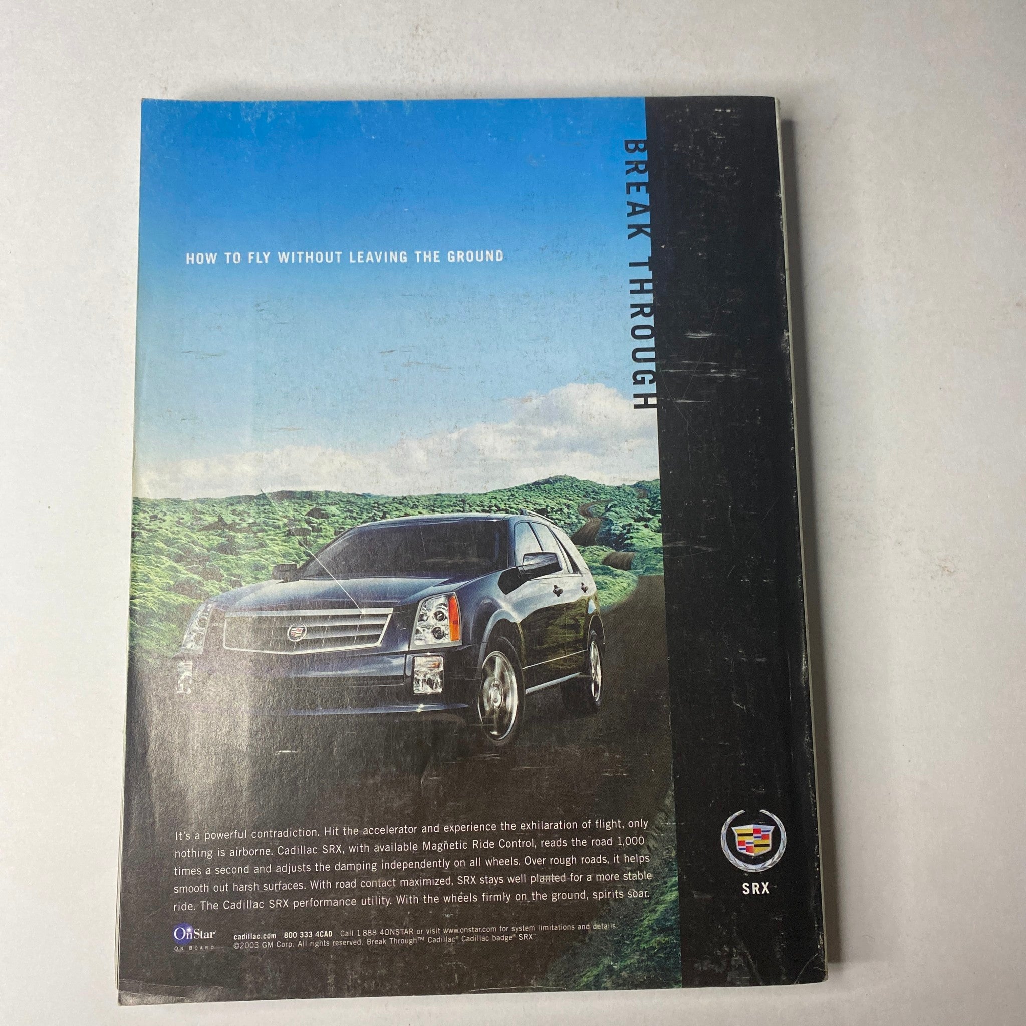 Back cover of Vogue Magazine November 2003 showcasing a Cadillac SRX SUV with a mountainous landscape background, emphasizing luxury and performance.
