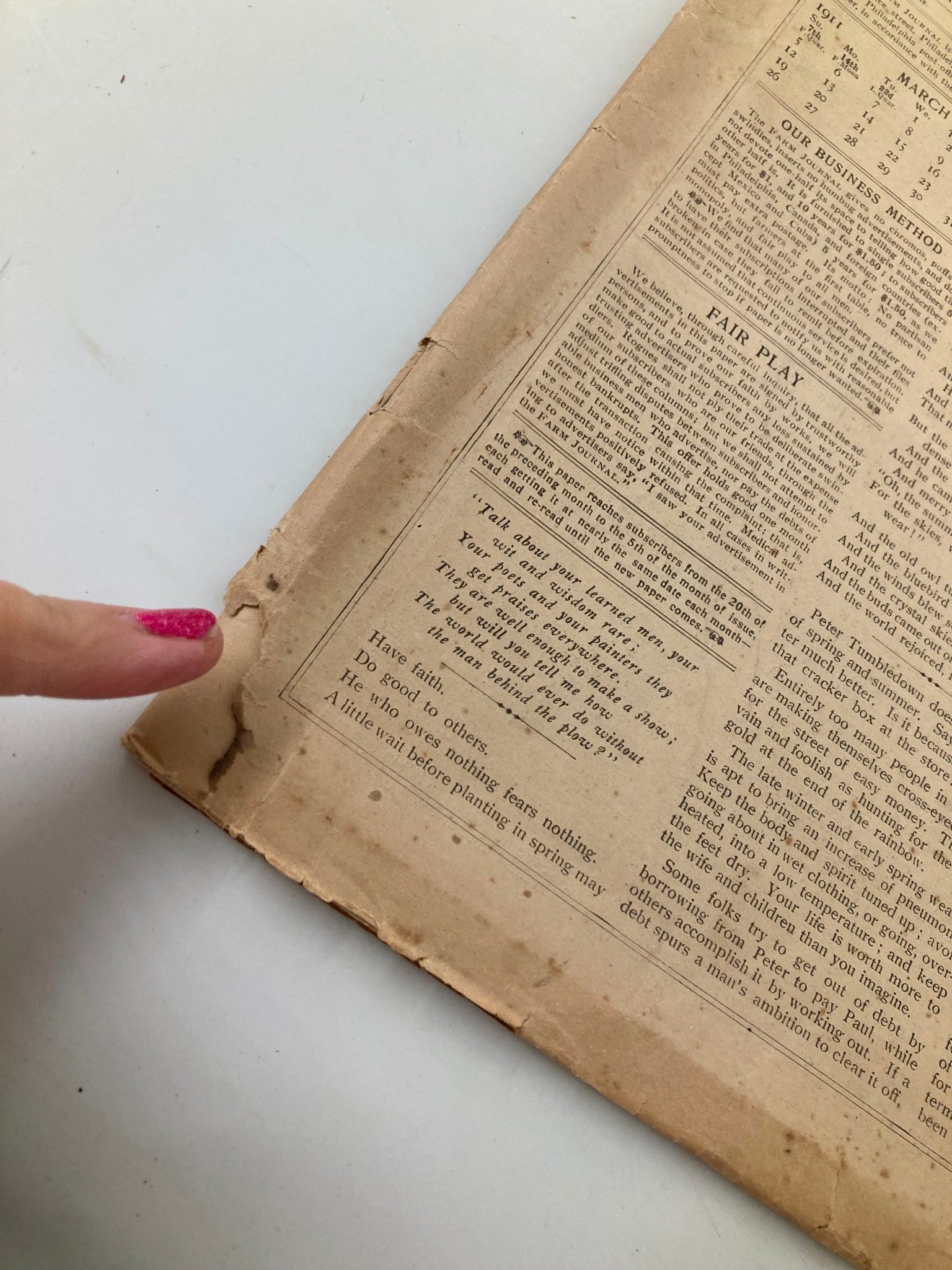 Condition detail of VTG The Farm Journal Magazine March 1911 showing wear on the bottom corner and a finger pointing at the damage.