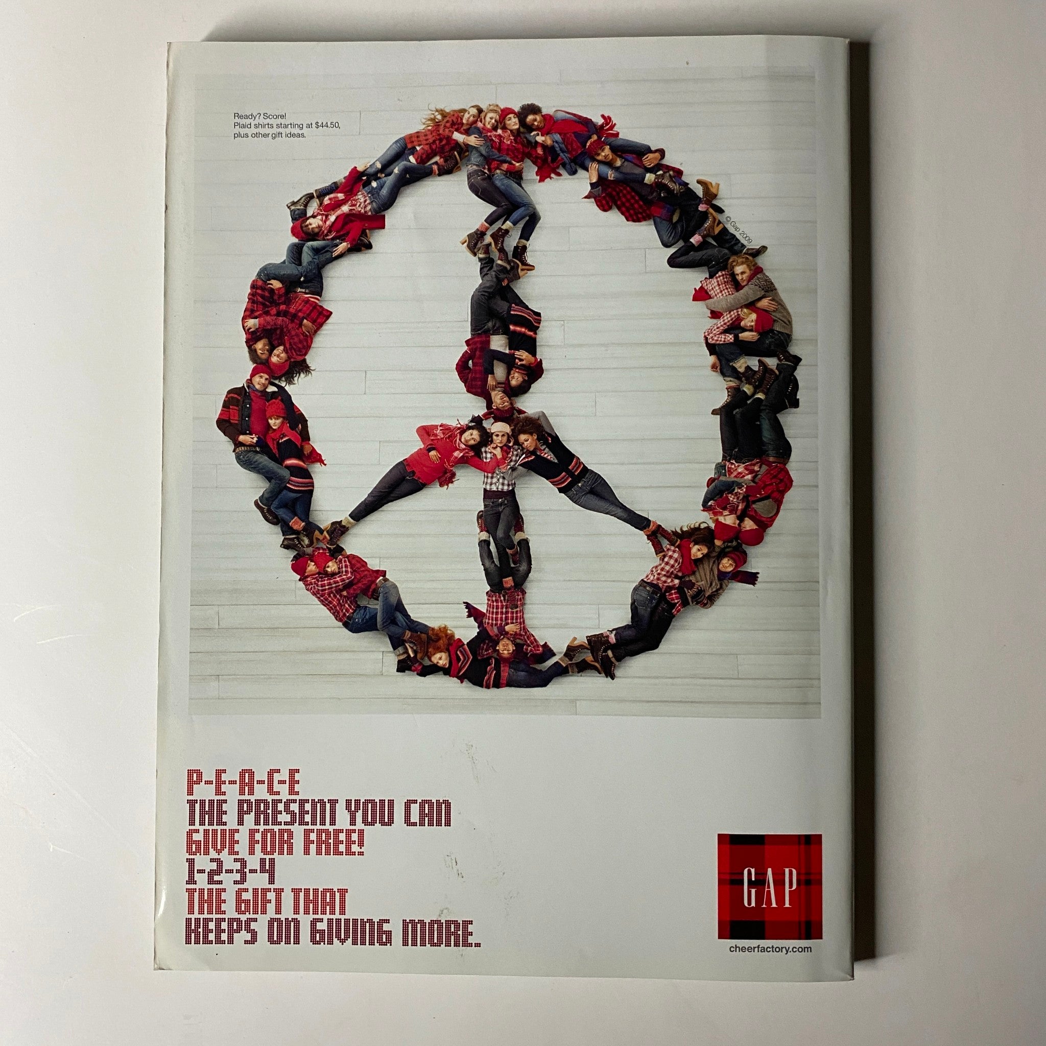 A Gap advertisement from Vogue Magazine December 2009 depicting a group of models arranged in a peace sign, promoting a message of peace and community during the holiday season.