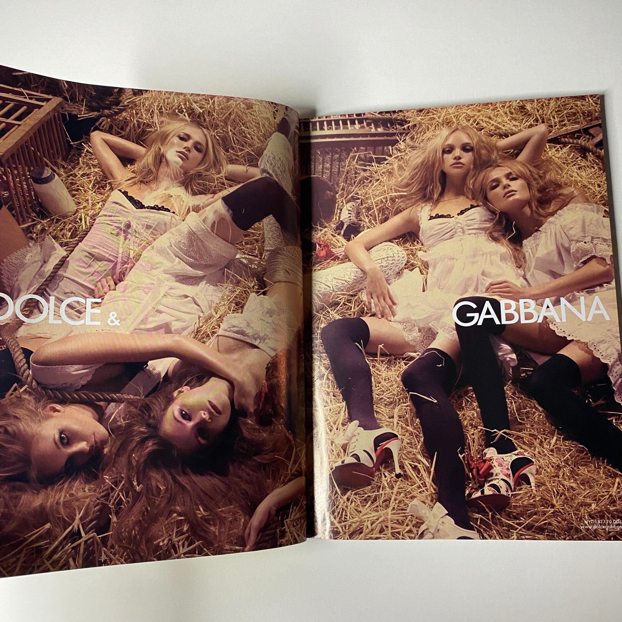 Fashion editorial spread from Vogue Magazine January 2006 featuring multiple models styled in Dolce & Gabbana outfits surrounded by hay, illustrating bold fashion choices.