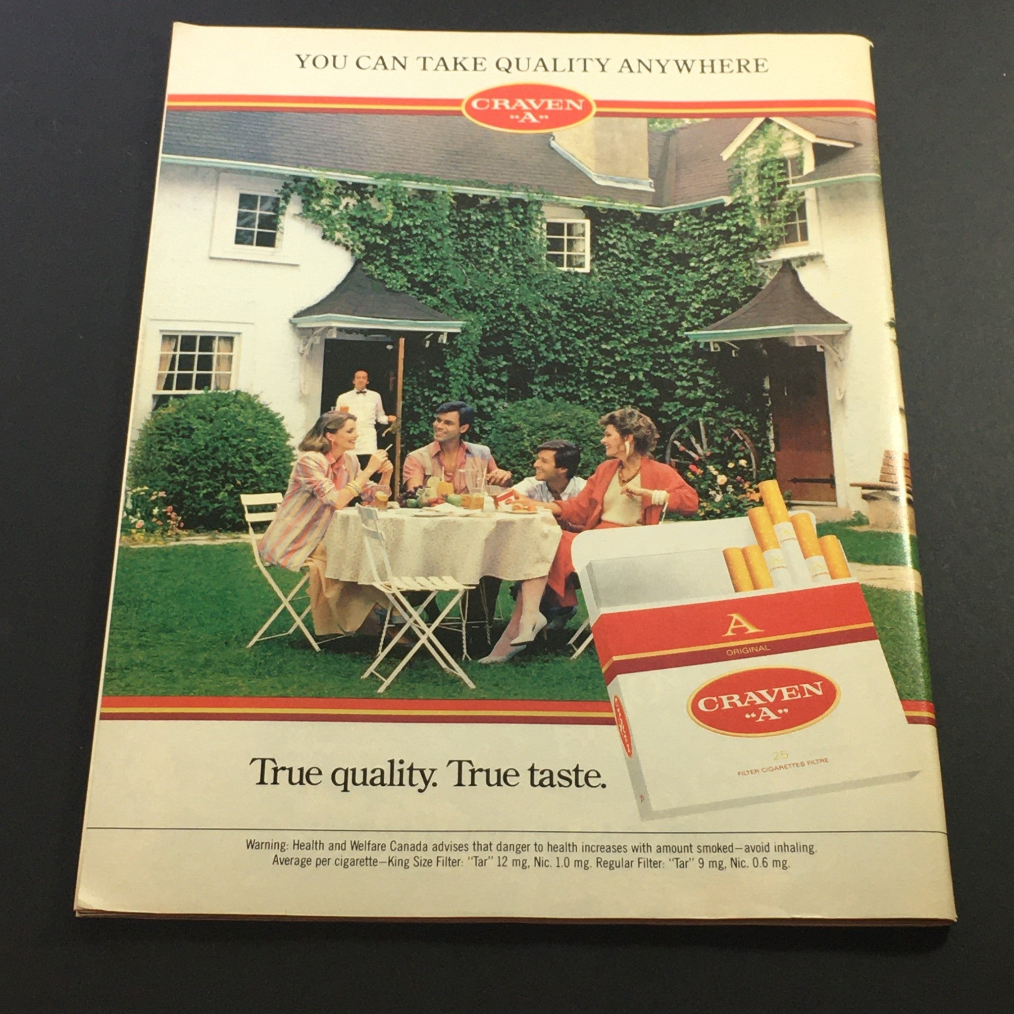 Back cover of the VTG Performance Theatre Magazine July-August 1986 featuring an advertisement for Craven-A cigarettes alongside a social gathering scene.