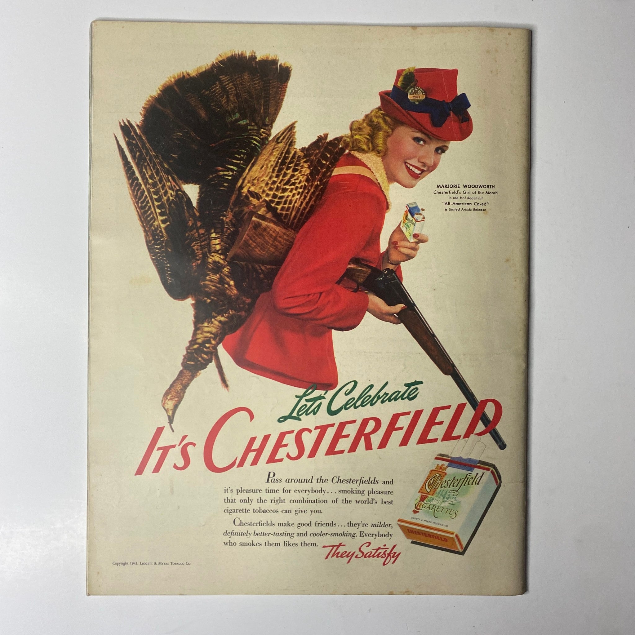 Vintage advertisement from Look Magazine November 4, 1941 featuring a woman in red attire holding a shotgun with a turkey, promoting Chesterfield cigarettes.