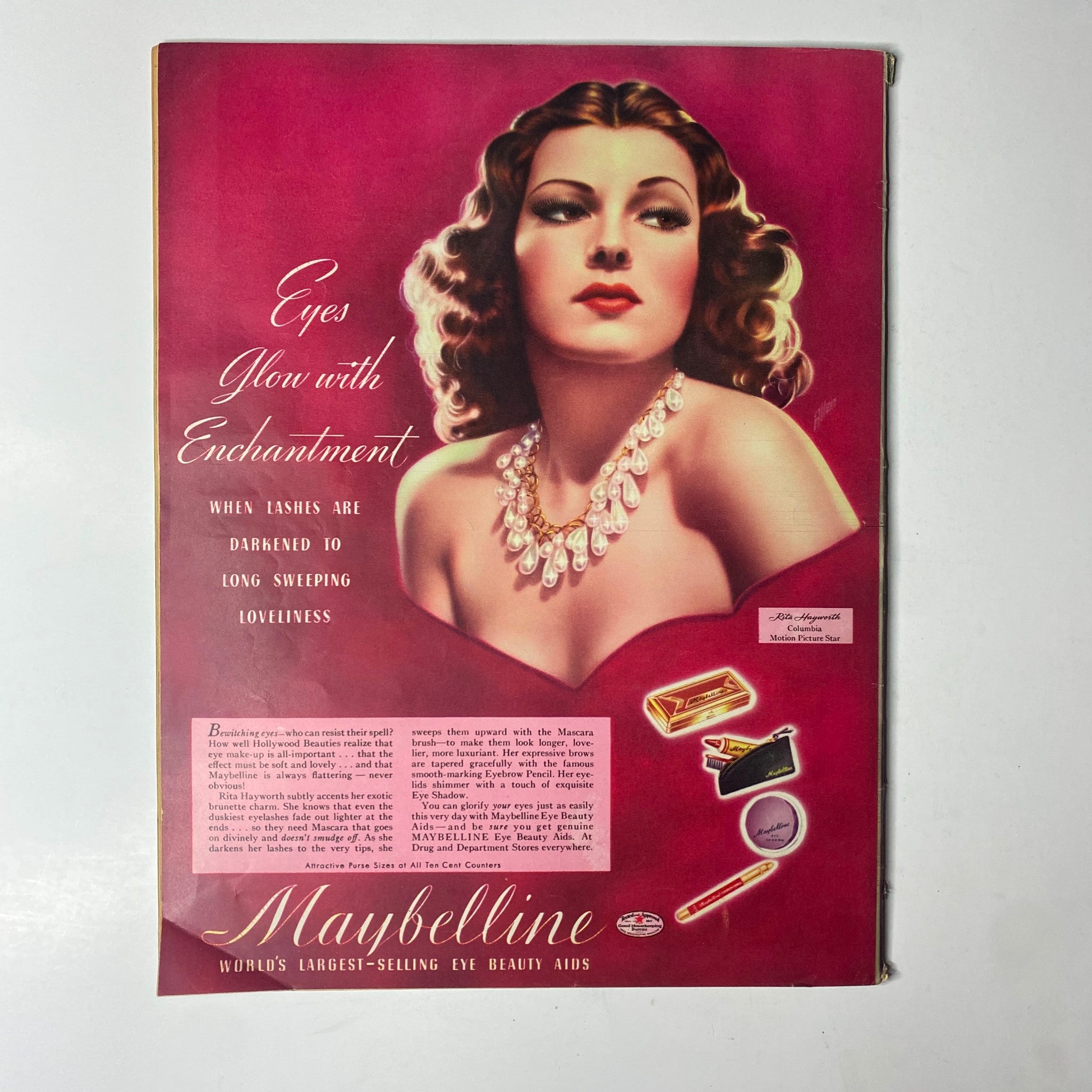 Vintage Maybelline advertisement featuring a glamorous woman with pearls and red background, promoting beauty aids, from Click Magazine April 1941 Vol. 4, No. 4 Girls on Parade Ziegfeld Girl.