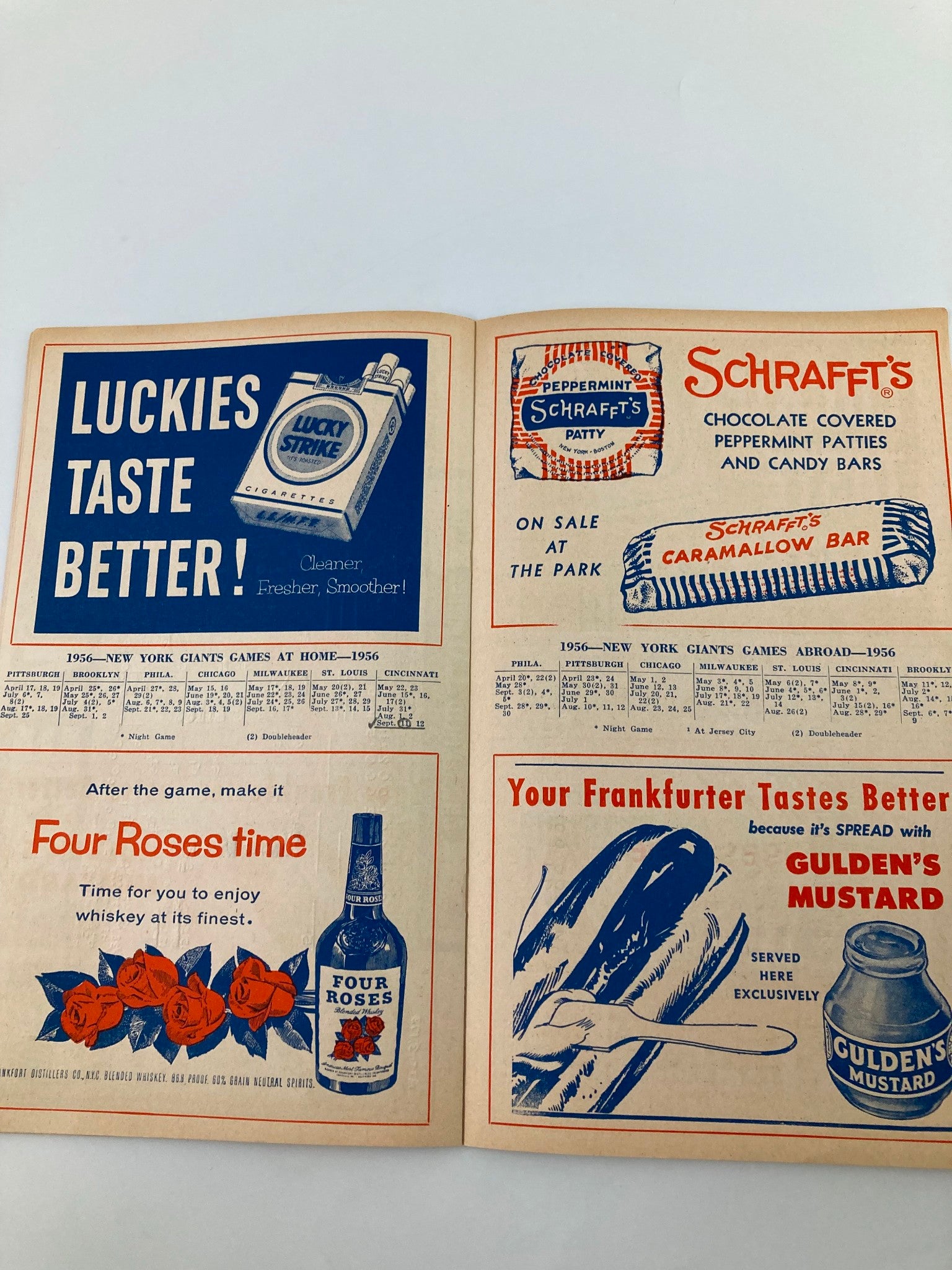 1956 MLB New York Giants Official Program and Score Card featuring advertisements for Lucky Strike cigarettes, Schraffts chocolate, and Four Roses whiskey, showcasing vintage memorabilia from baseball history.