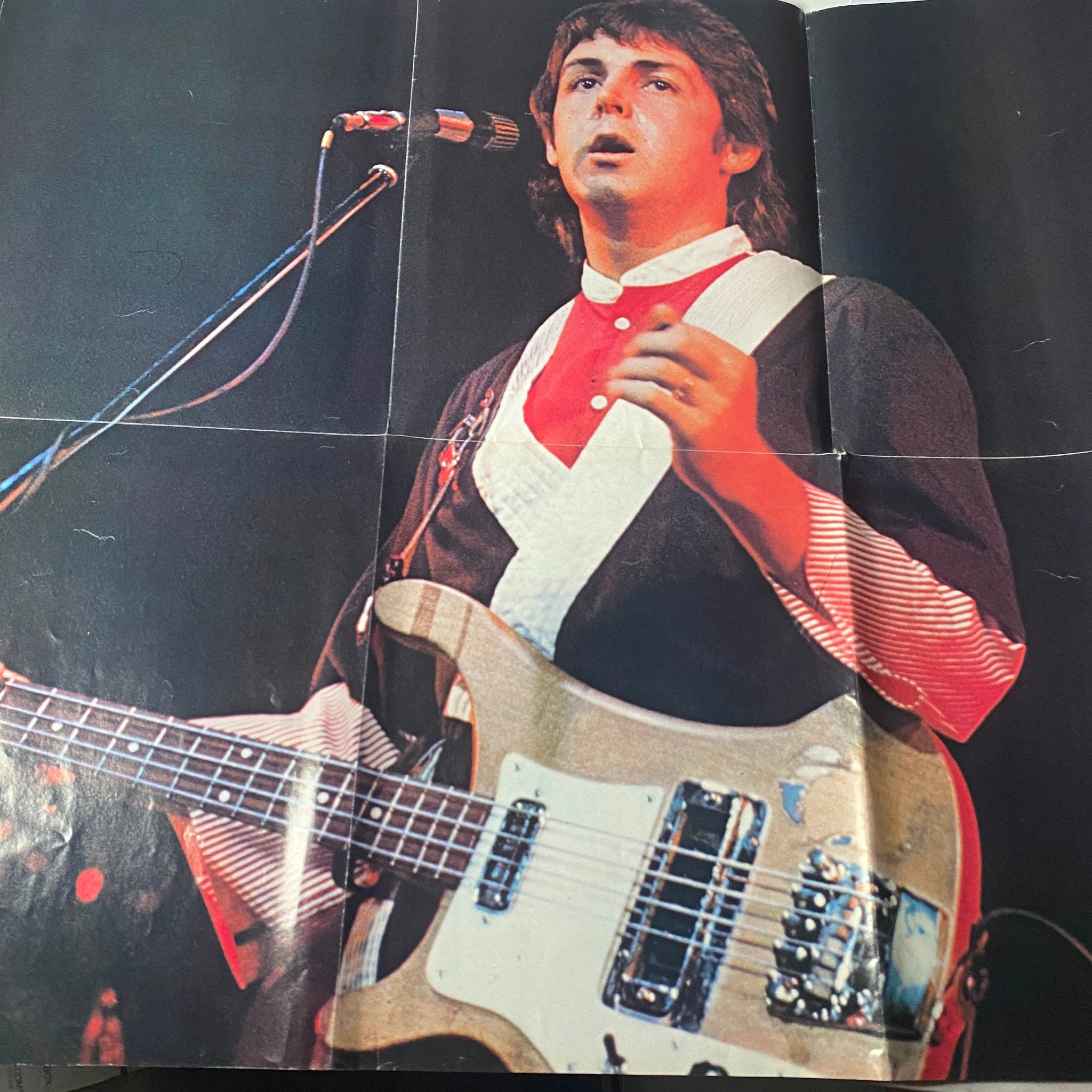 Centerfold image of Paul McCartney performing live in the Rock Superstars Poster Magazine 1975 No. 7, showcasing his musical talent during the Wings era.