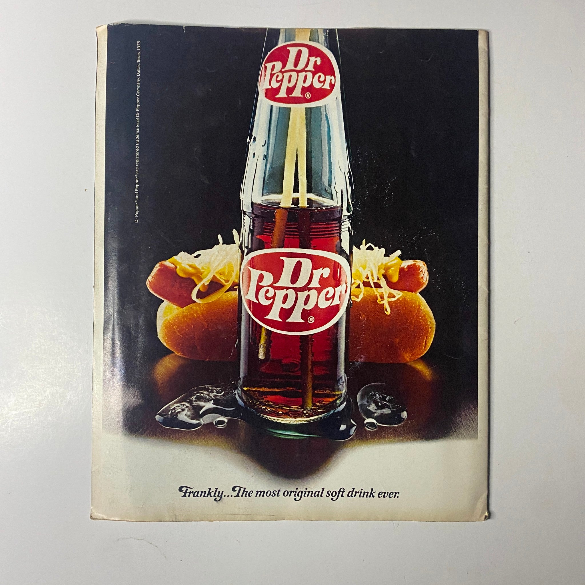Cover of a vintage advertisement for Dr. Pepper featuring a glass bottle of the soft drink and hot dogs, illustrating classic 1970s Americana and nostalgia, included in the collectibles of the Rock Superstars Poster Magazine 1975 No. 7.