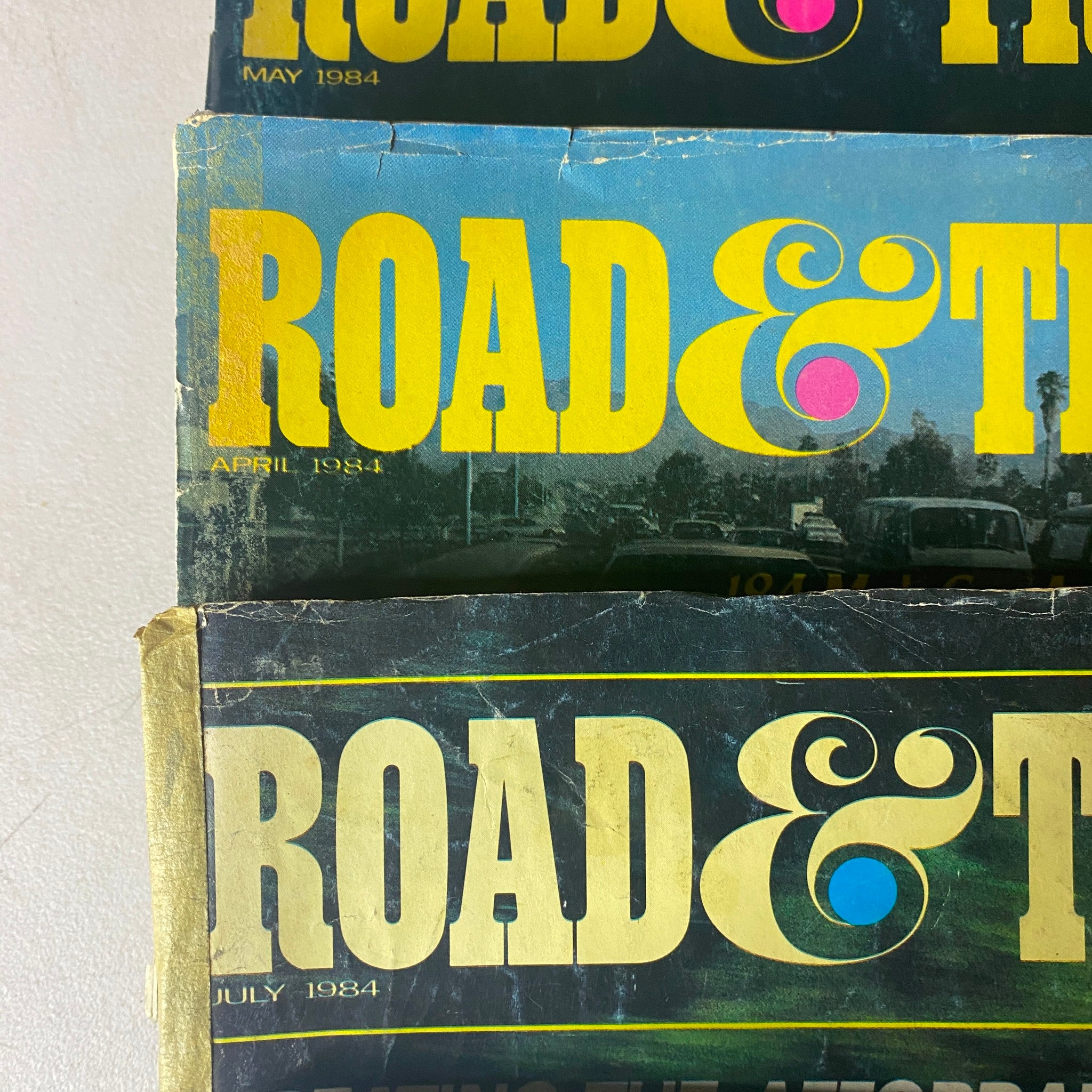 Close-up view of three Road & Track Magazine covers from April, May, and July 1984, highlighting the classic designs and featured automotive content.