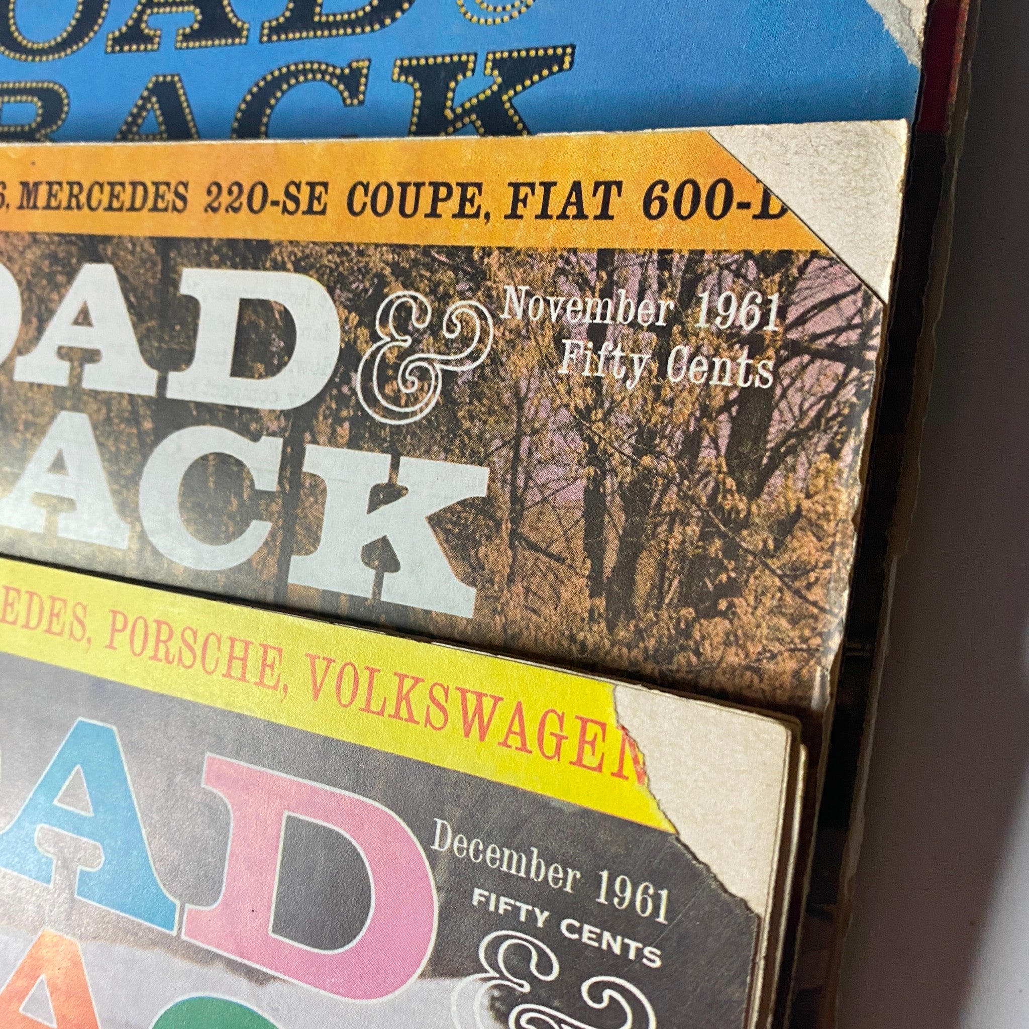 Close-up of November and December 1961 issues of Road & Track Magazine from the 12 magazine collection, featuring classic cars such as Mercedes and Volkswagen.