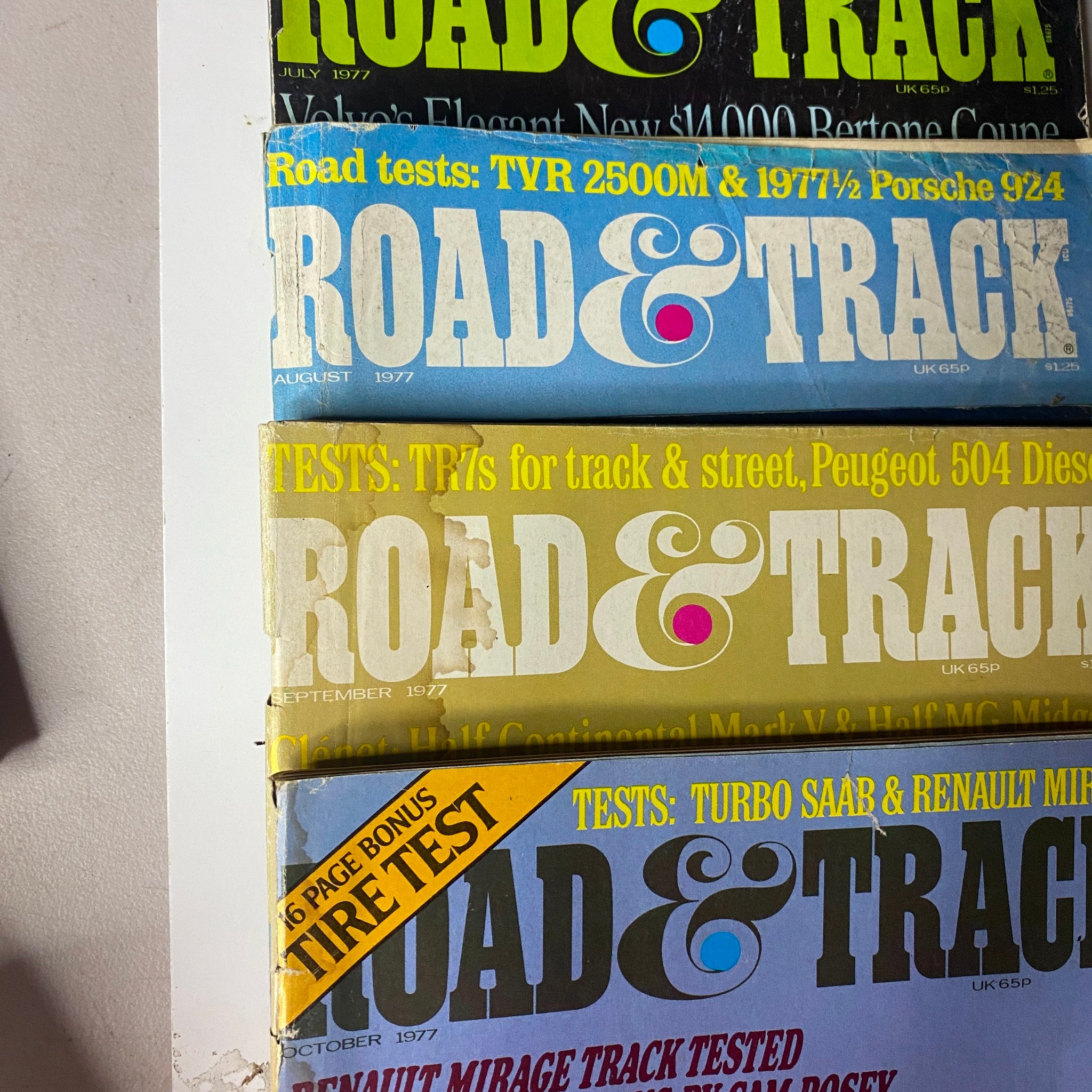 Lot of 24 Road & Track Magazine 1976 - 1979, highlighting issues from August and September 1977, with diverse car evaluations and features.