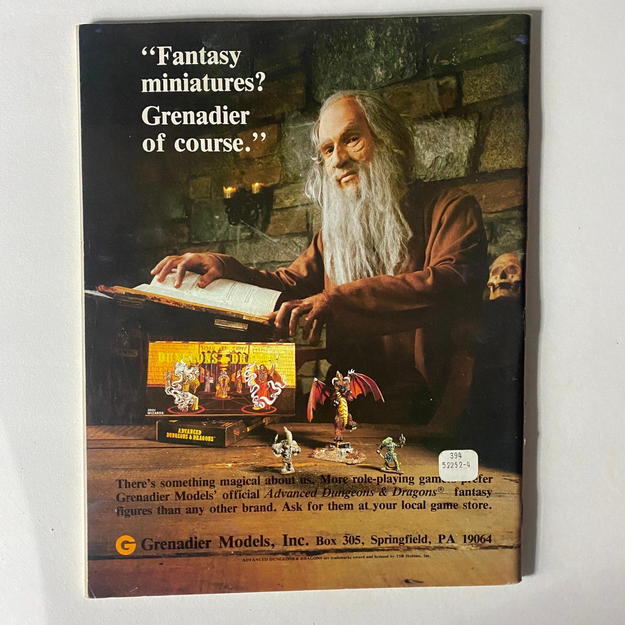 Back cover of Dragon Magazine January 1982 Issue #57 featuring a wizard promoting Grenadier fantasy miniatures with a display of gaming figures.