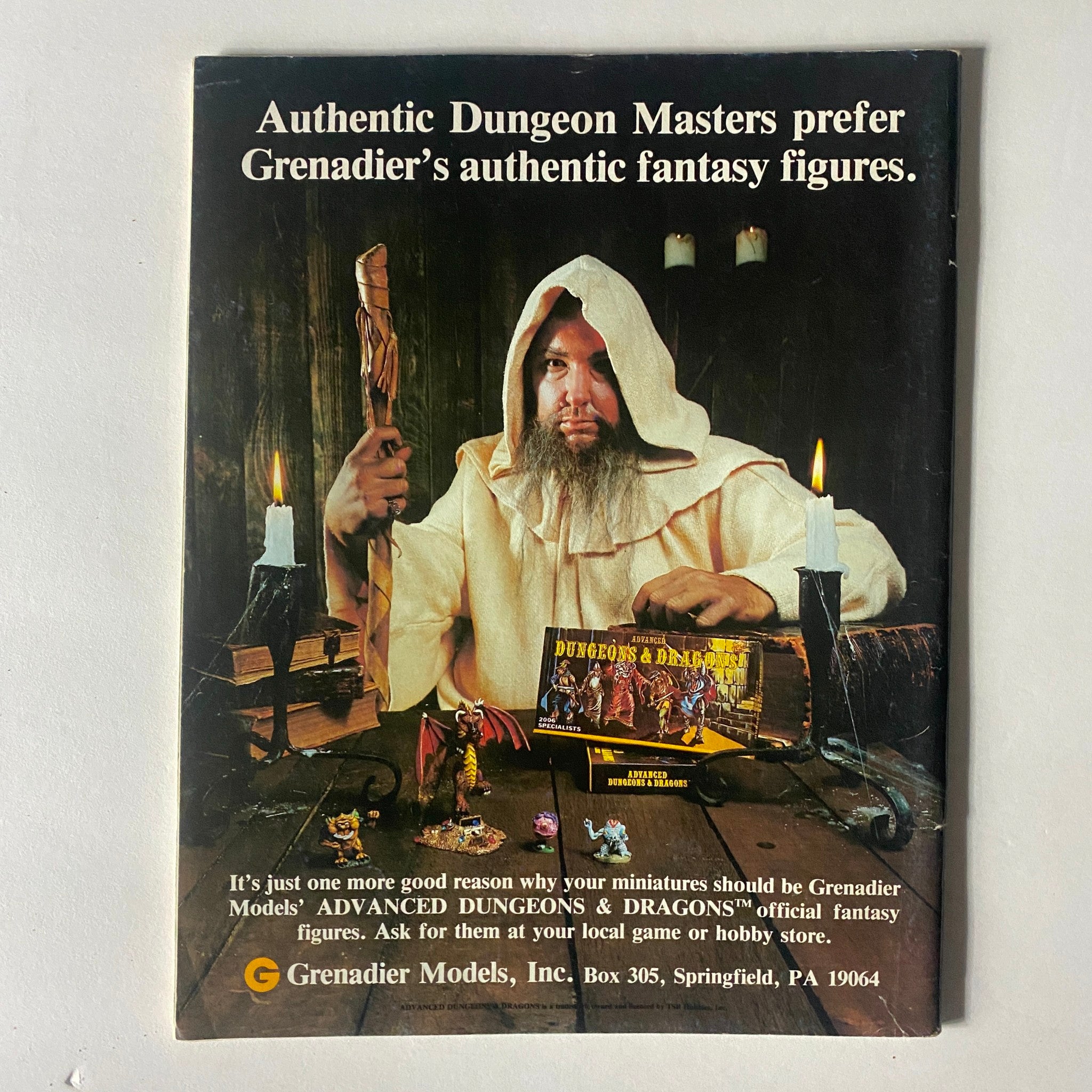 Vintage advertisement for Grenadier Models featuring a Dungeon Master with fantasy figures, promoting authentic Dungeons & Dragons miniatures, in the context of Dragon Magazine June 1982, Issue #62.