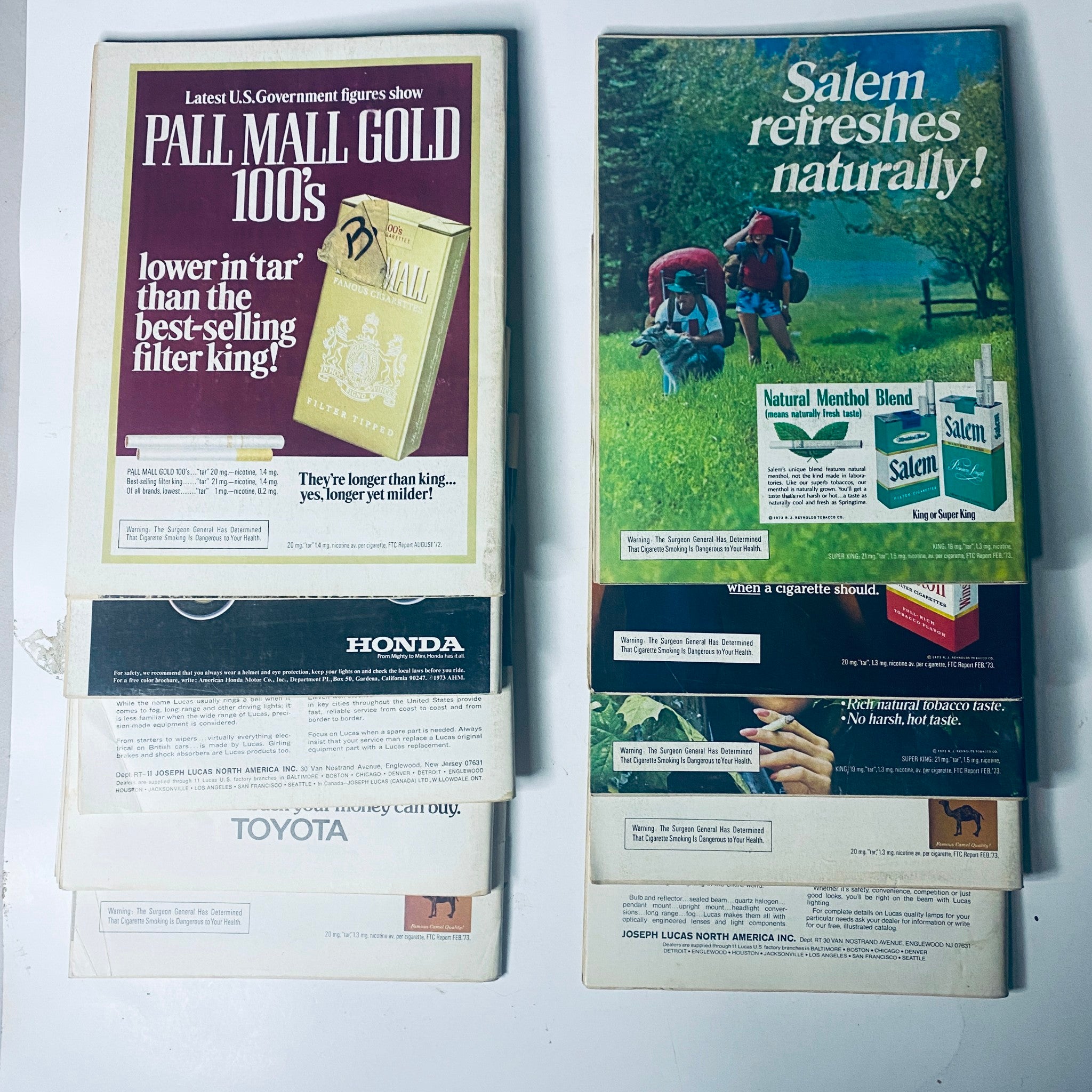 Back cover of Road and Track Magazine issues featuring advertisements for popular brands like Pall Mall, Honda, and Toyota, reflecting vintage automotive culture.