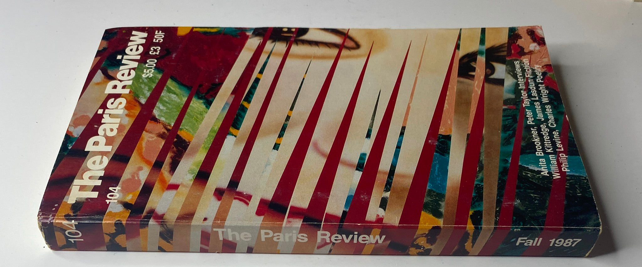 Side view of The Paris Review Magazine No. 104, Fall 1987, showcasing the spine and colorful cover design, indicating features like interviews and fiction from notable authors and poets.