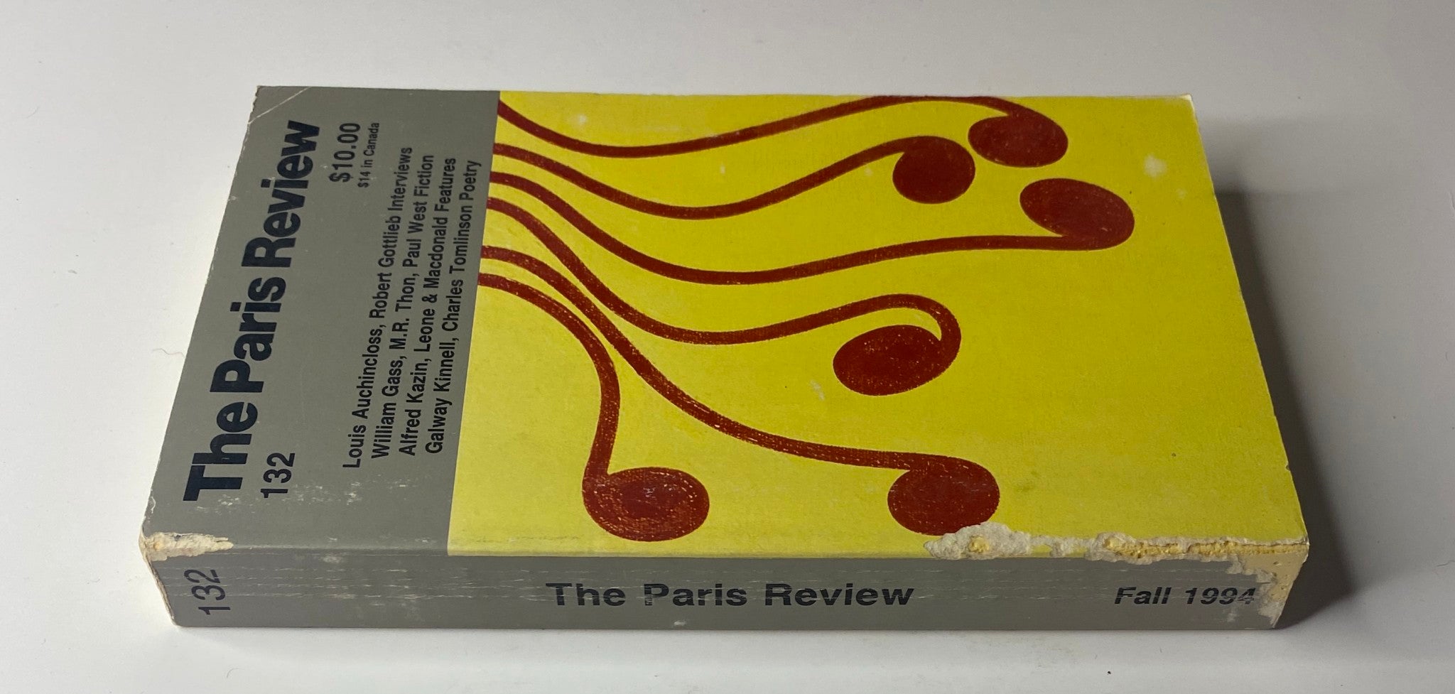 Side view of The Paris Review Magazine Fall 1994 No. 132 showing edge wear and the title prominently displayed alongside a yellow design with musical notes.