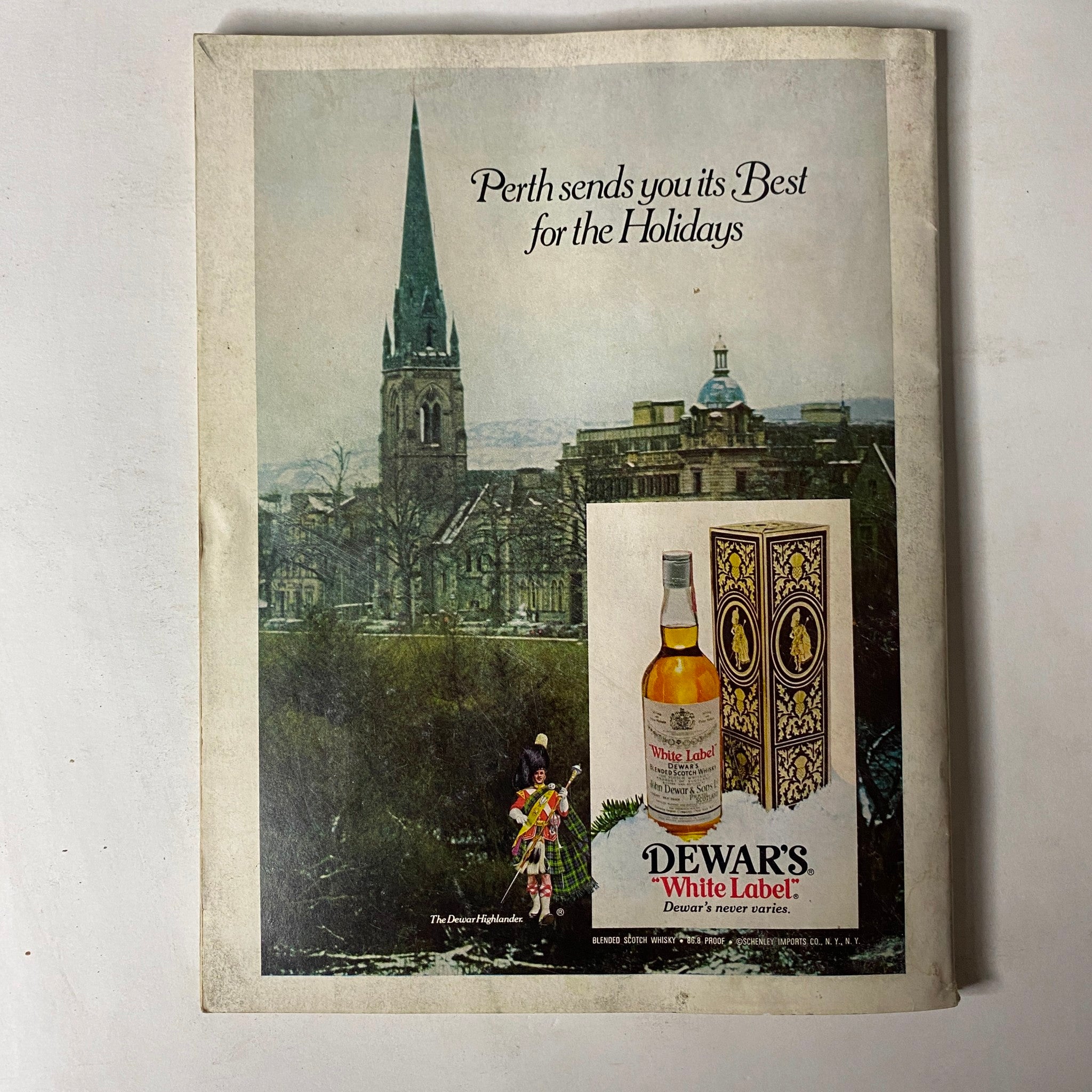 Back cover of GQ Magazine Winter 1975-1976 featuring a scenic advertisement for Dewar's White Label whiskey, promoting holiday spirits with a picturesque view.