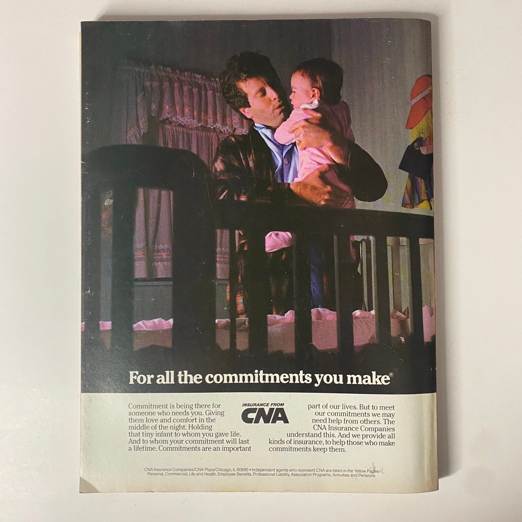 Vintage advertisement from Forbes Magazine 1985: The Richest People in America Special Edition depicting a father holding his baby, emphasizing the theme of commitment and insurance from CNA.