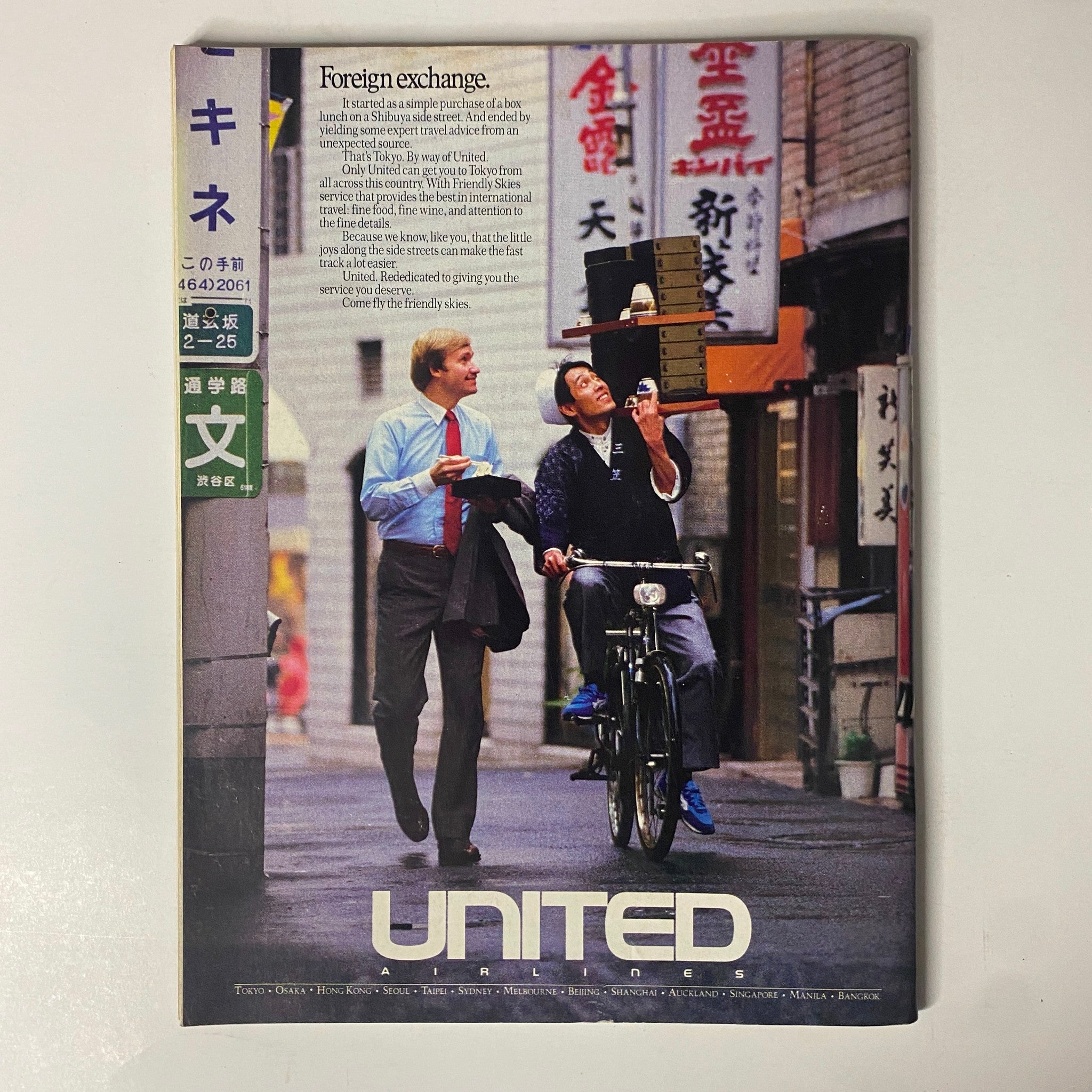 Cover page of United Airlines advertisement in Forbes Magazine October 17, 1988, depicting a friendly interaction in Tokyo, symbolizing international travel.