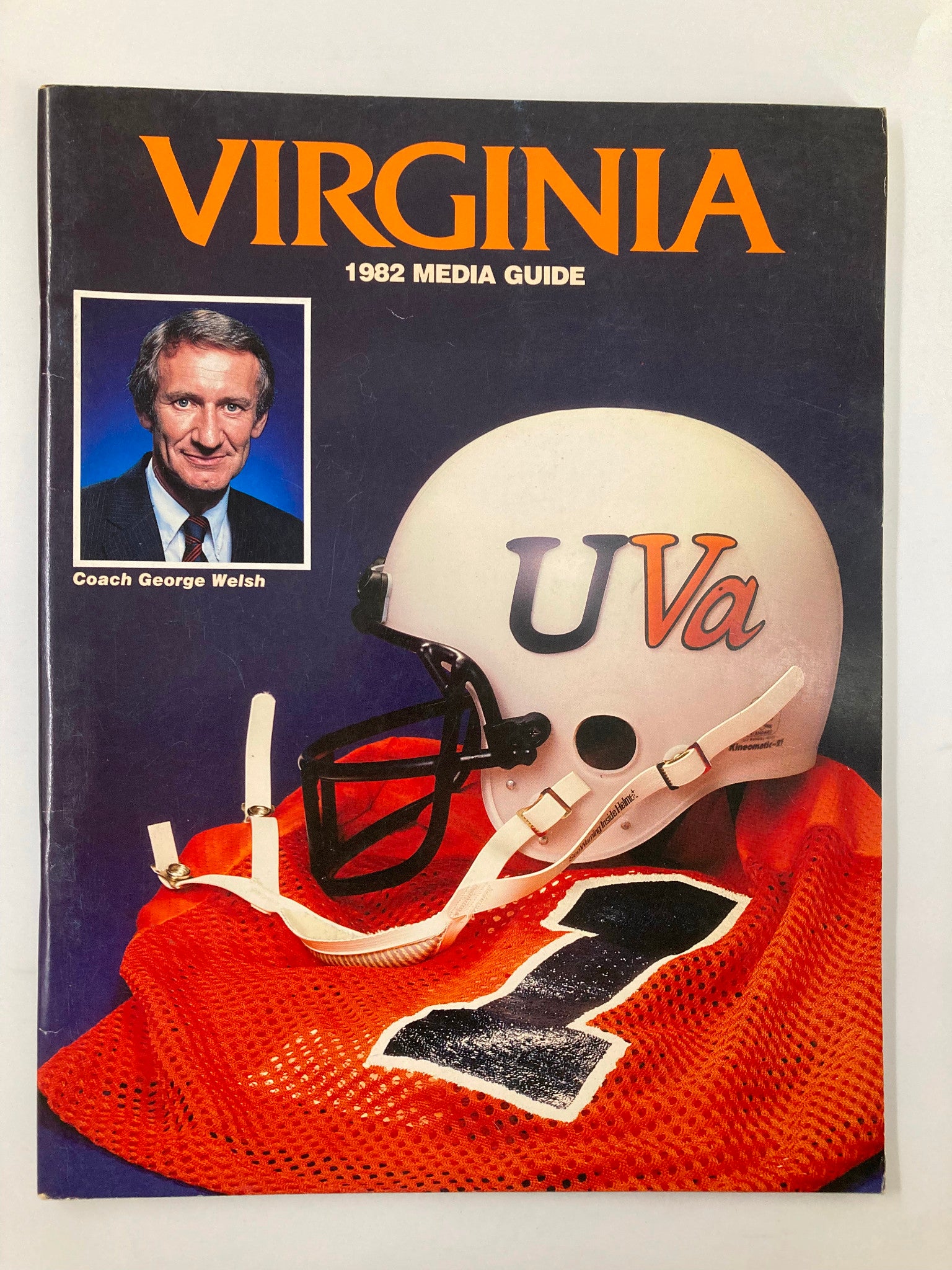 Cover of VTG 1982 The Football Virginia Media Guide featuring Coach George Welsh with a helmet and jersey background.