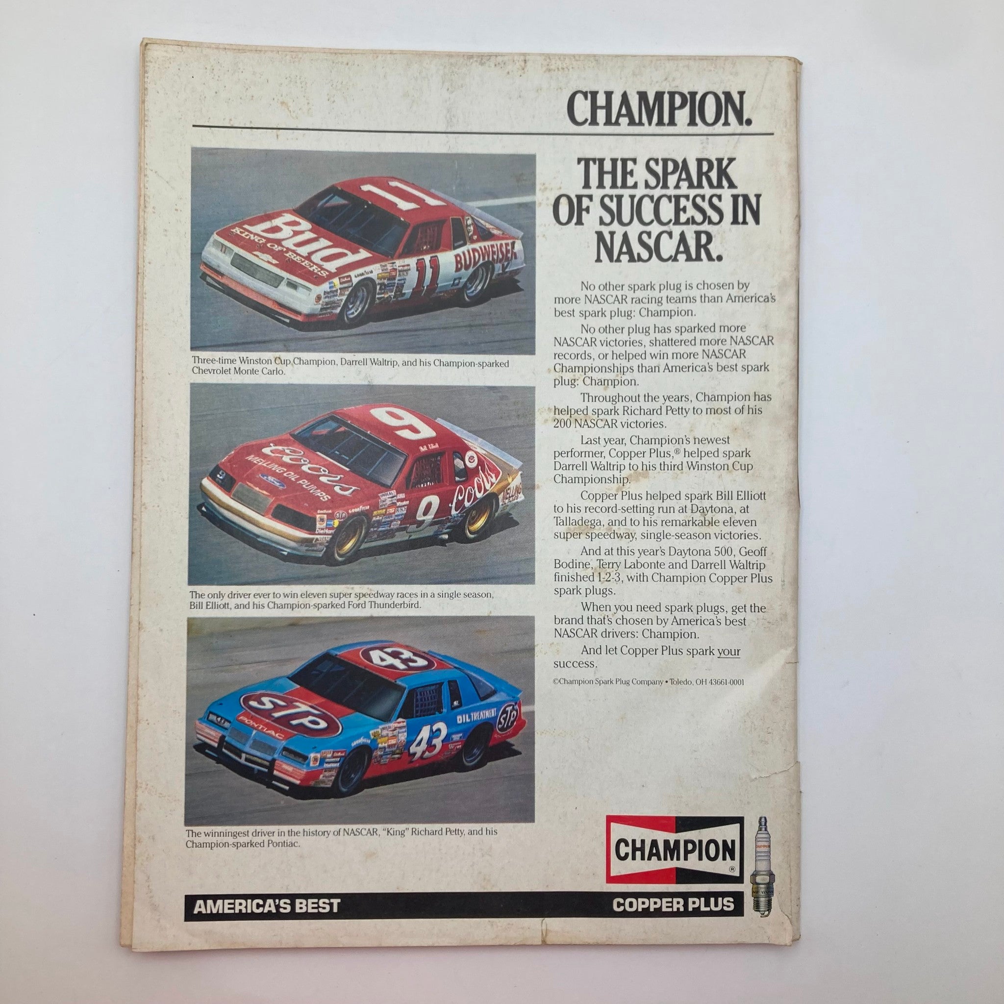 Back cover of the VTG Stock Car Racing Magazine September 1986 featuring a Champion Spark Plug advertisement showcasing iconic NASCAR race cars. Highlighted cars include Darrell Waltrip's Chevrolet Monte Carlo and Bill Elliott's Ford Thunderbird, reflecting the excitement of 1980s stock car racing.