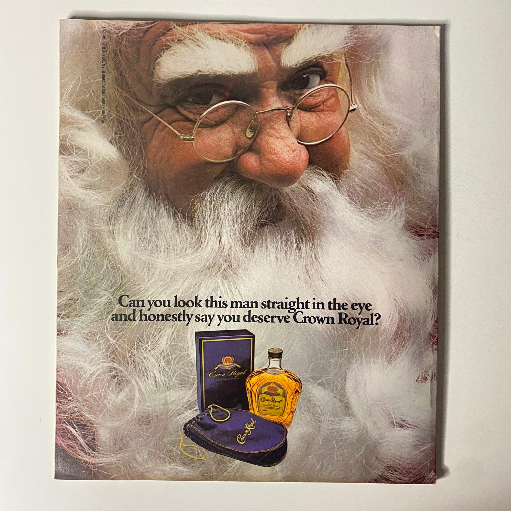 Cover of a vintage advertisement featuring a thoughtful Santa Claus promoting Crown Royal whiskey with an intriguing question.